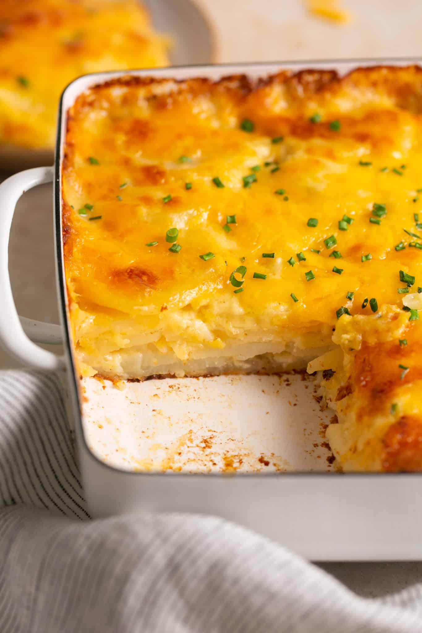 scalloped potatoes in a casserole dish garnished with chives on top. 