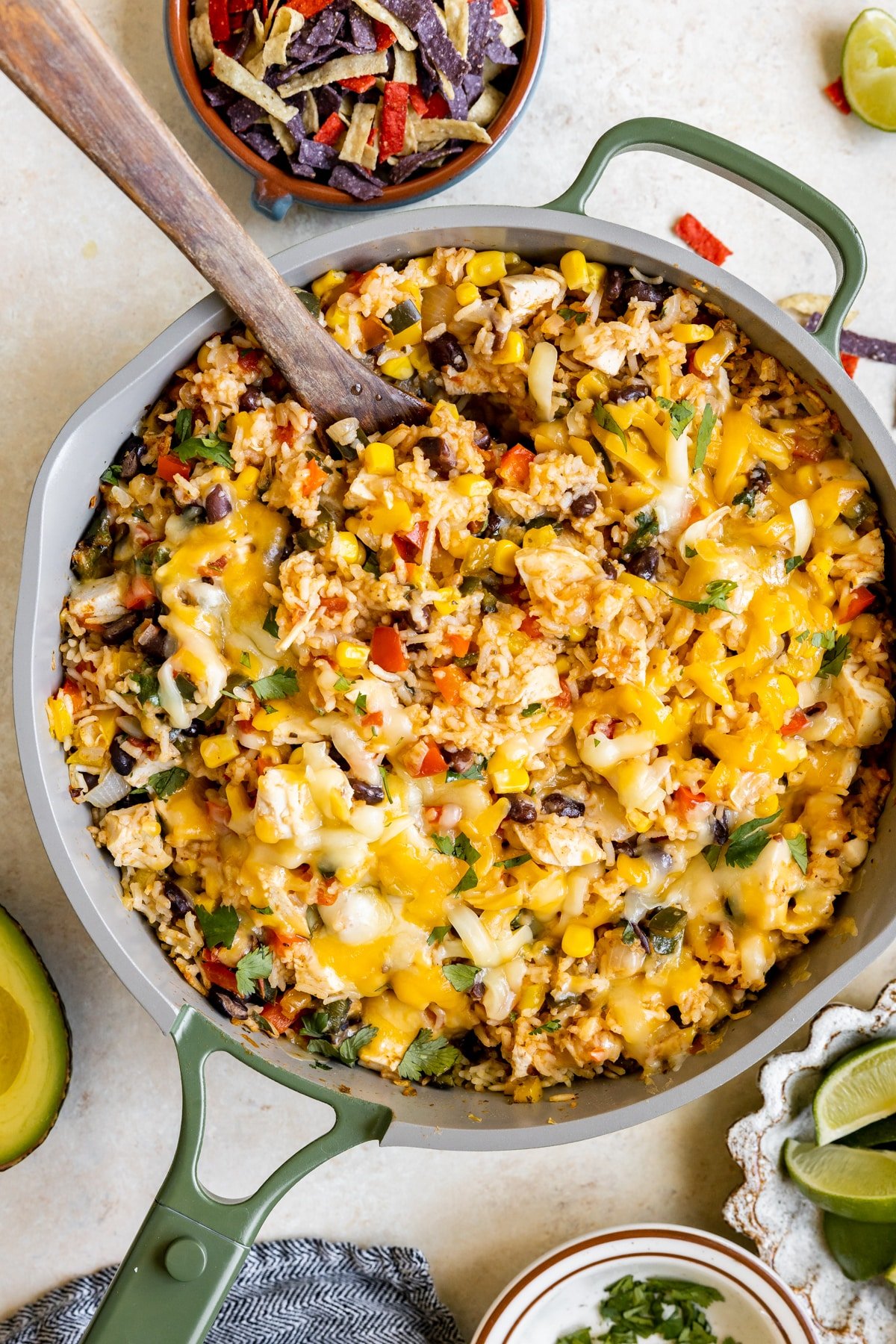 chicken, rice, beans and bell peppers in a skillet with cheese and cilantro on top. 