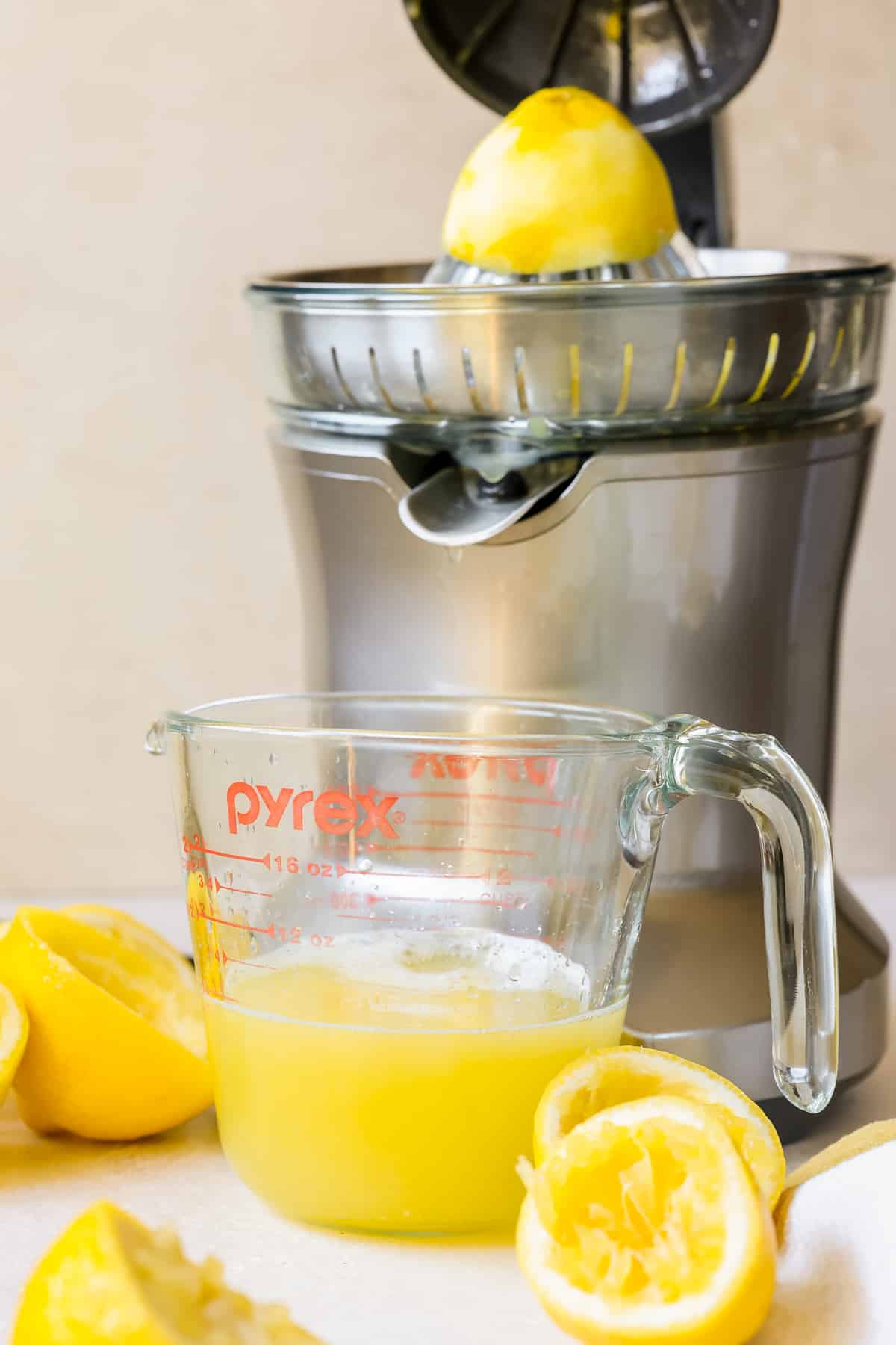 a citrus press juicing lemons into a measuring cup. 