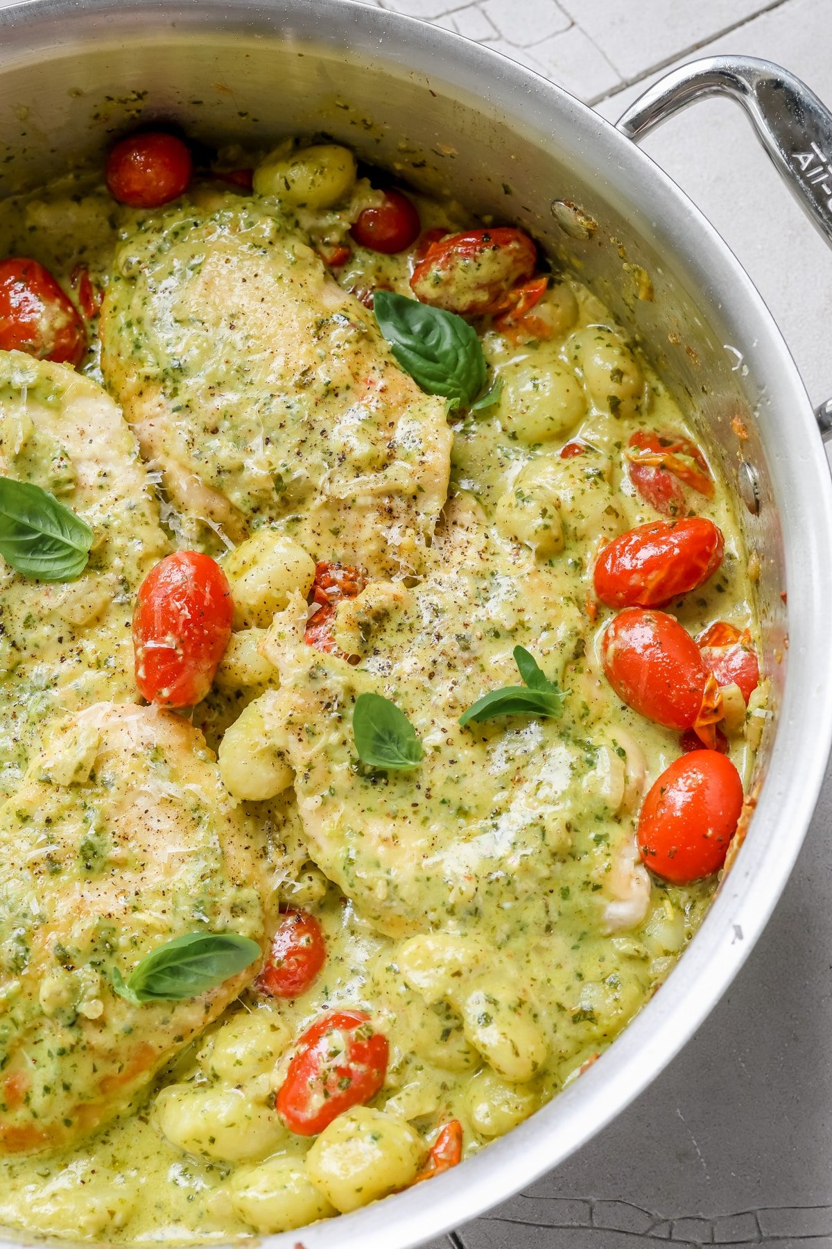 chicken, pesto and gnocchi in a skillet garnished with basil and black pepper. 