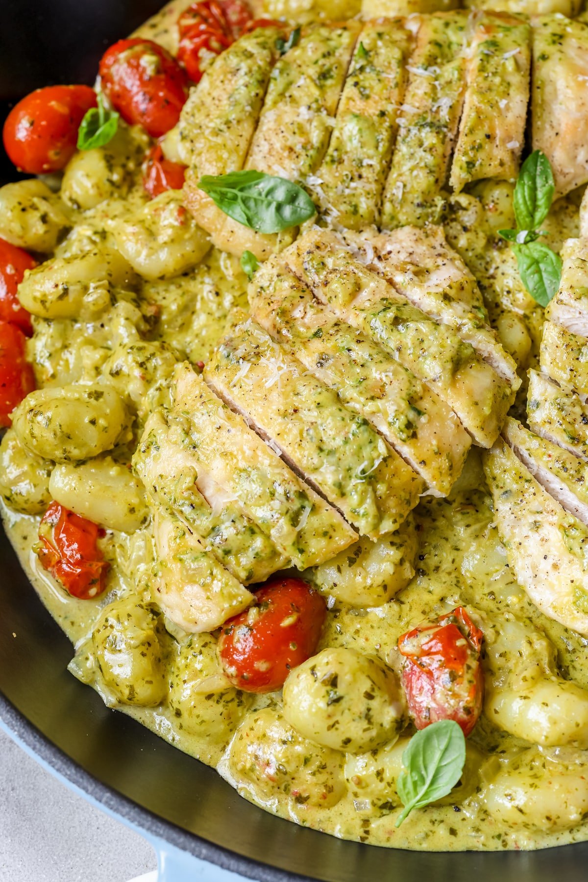 chicken, pesto and gnocchi in a skillet garnished with basil and black pepper. 