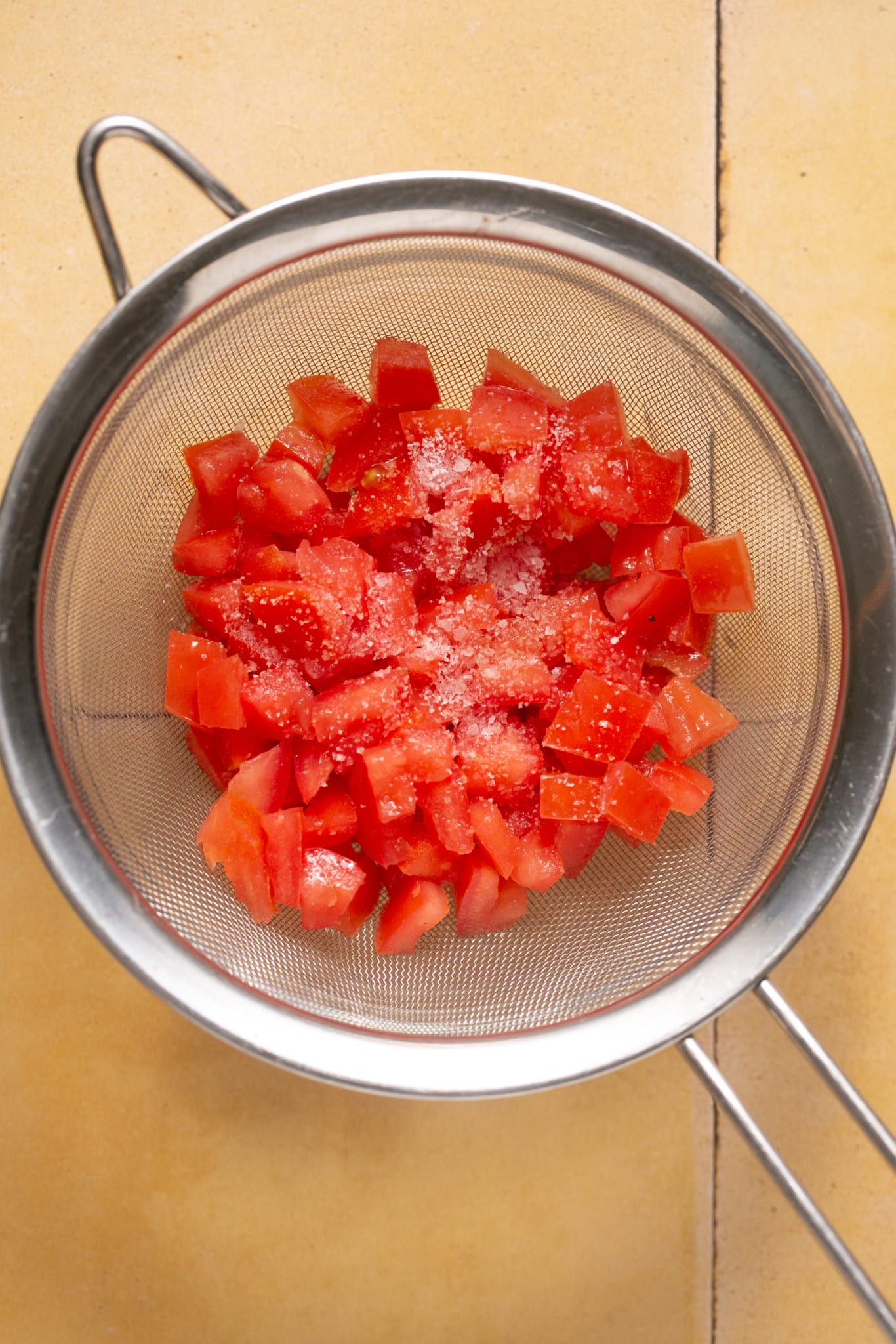 diced tomatoes in a strainer with salt on them