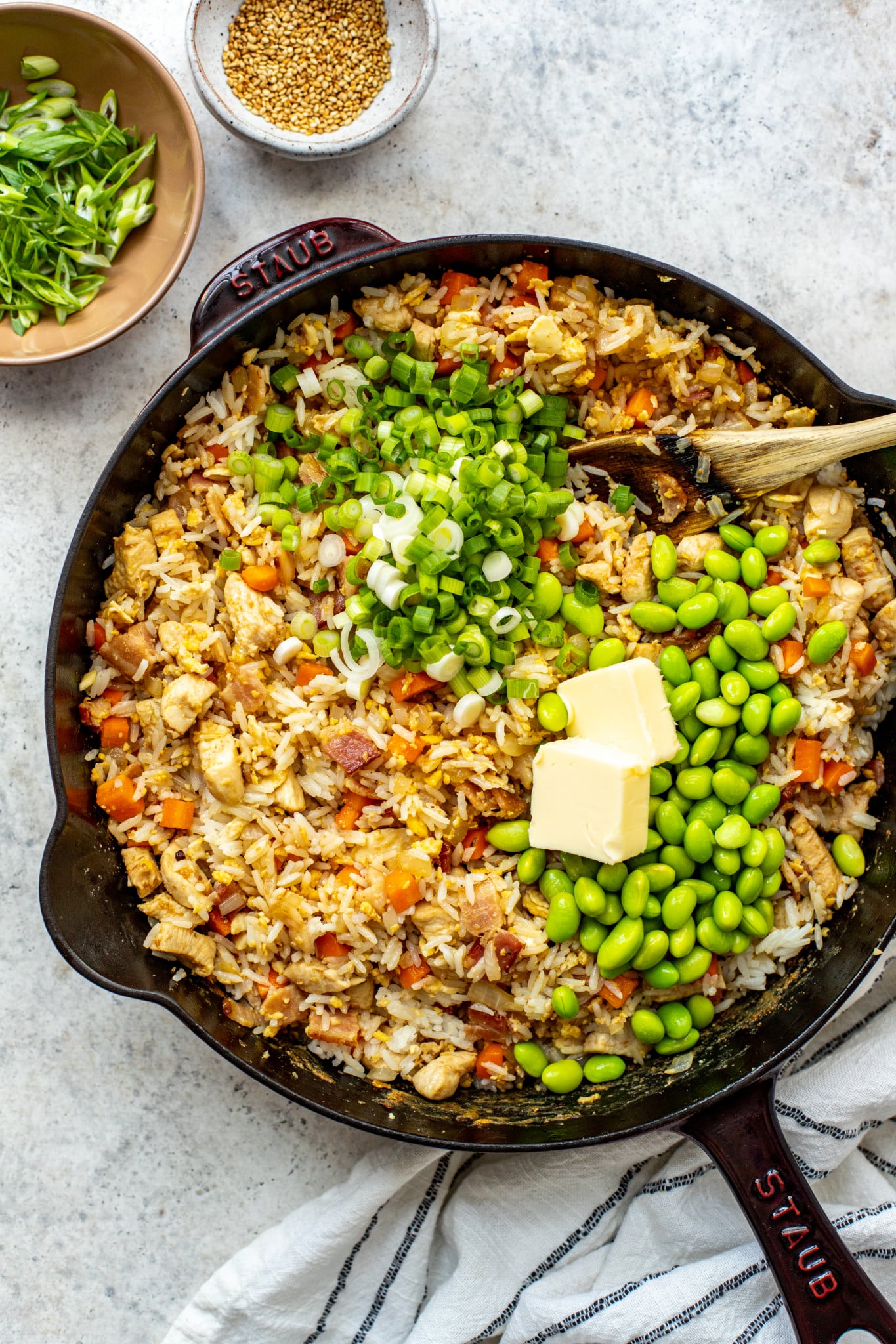 fried rice in a cast iron pan with green onions and edamame. 