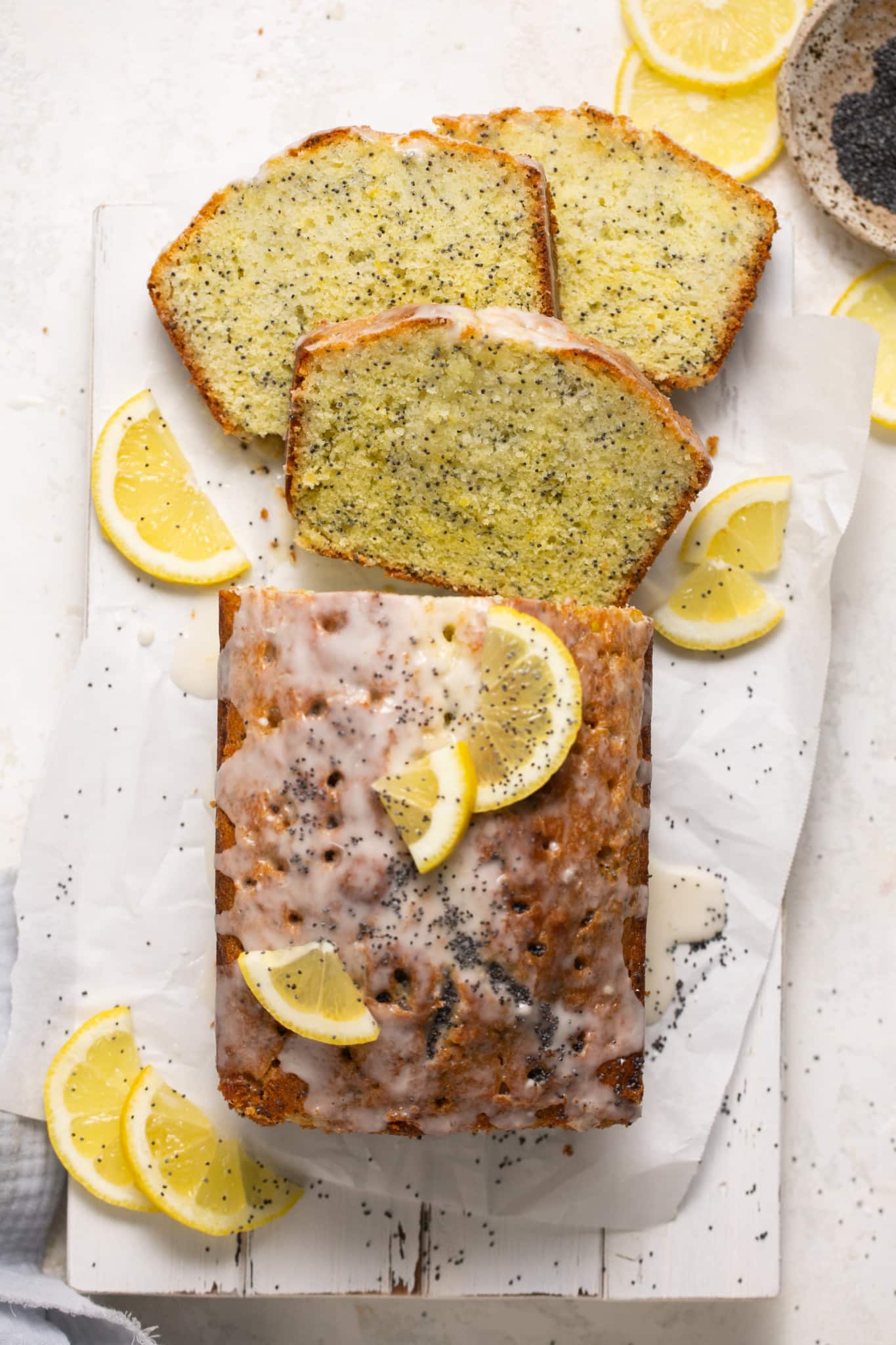 lemon poppyseed cake on parchment paper with a glaze on top.
