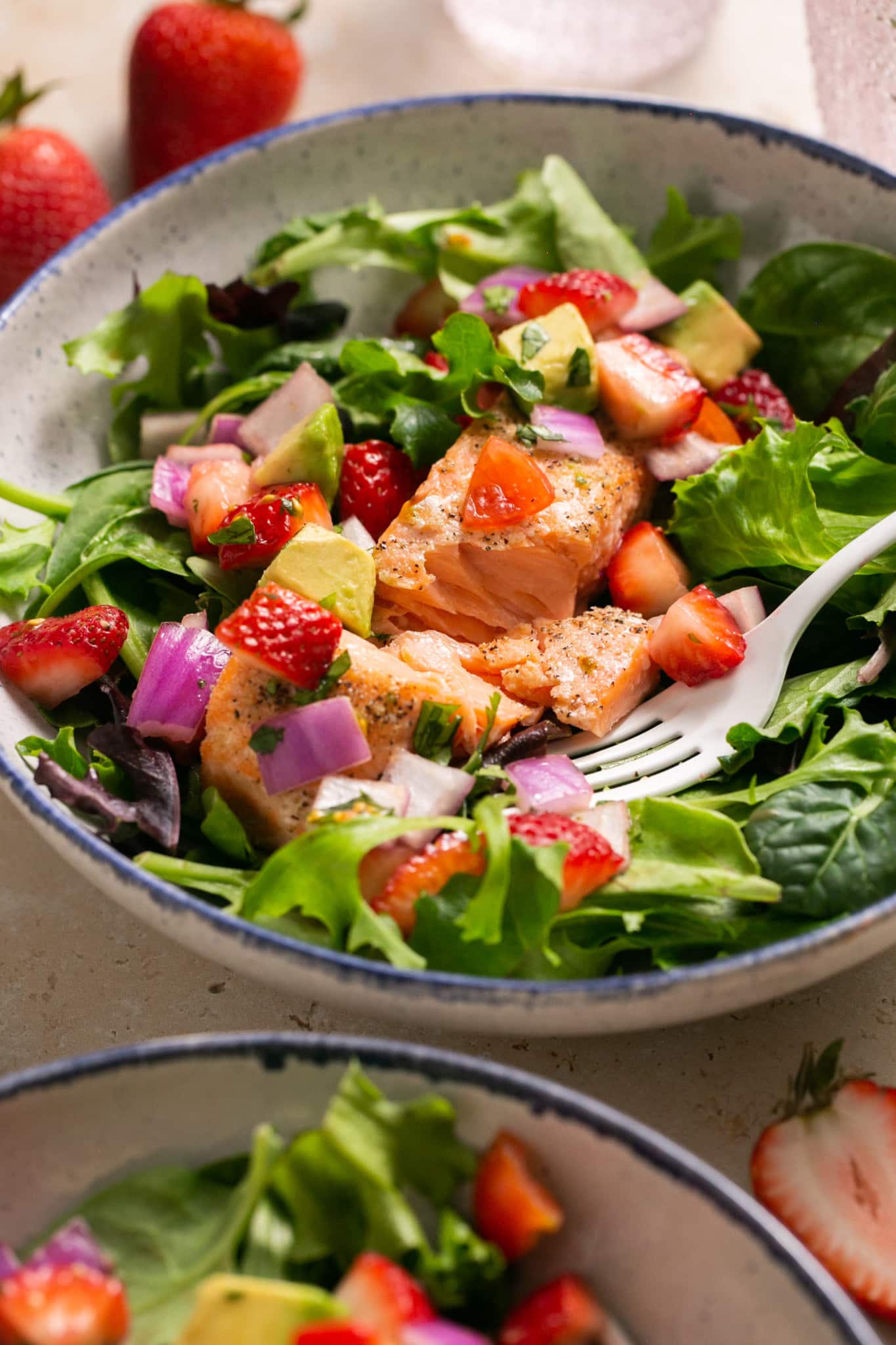 salmon on a green salad in blue bowls. 