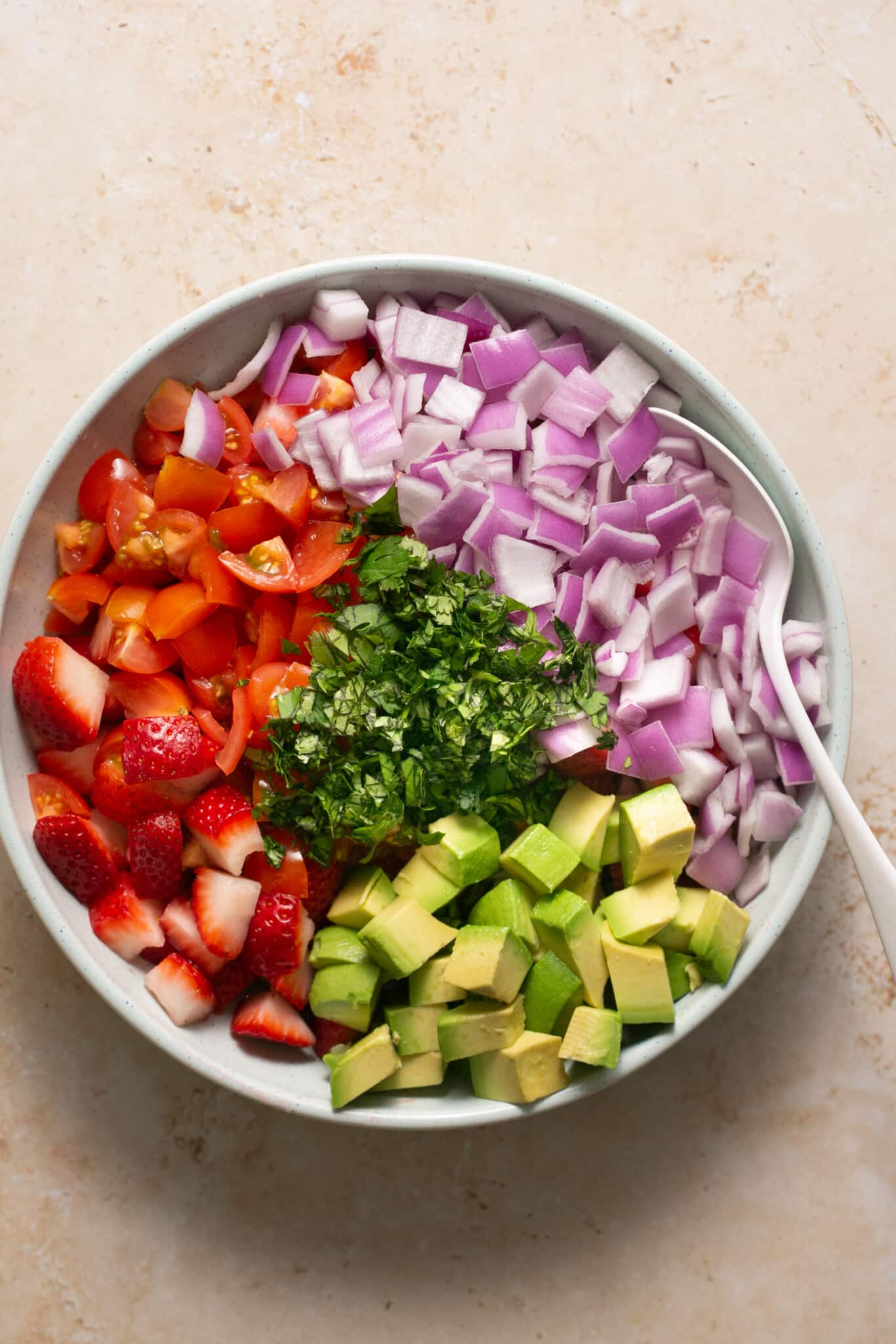 ingredients to make strawberry salsa in a large white bowl.