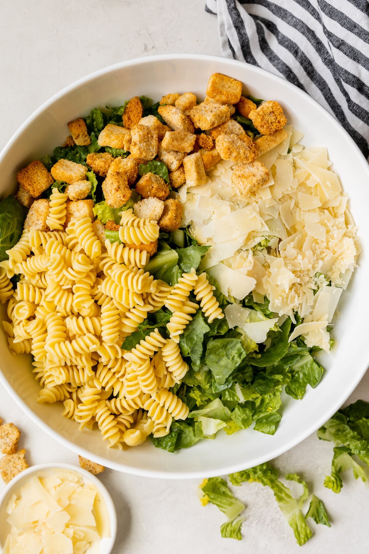 romaine in a bowl with rotini, shaved parmesan and croutons. 