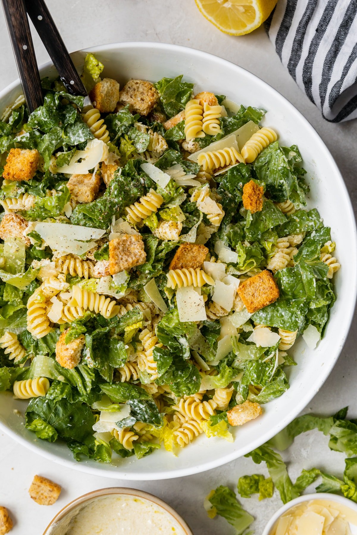 caesar salad in a bowl with parmesan cheese, croutons and rotini pasta.