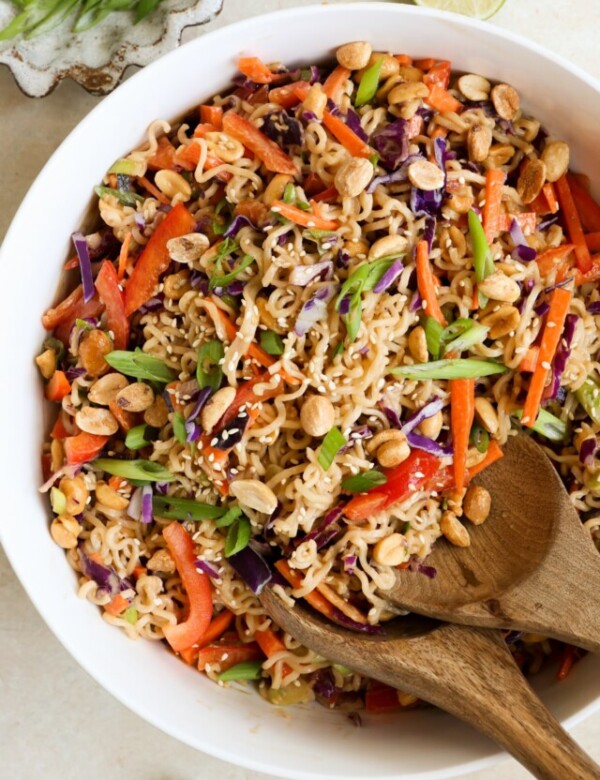 white bowl filled with an asian salad with ramen noodles, chopped veggies, and peanuts