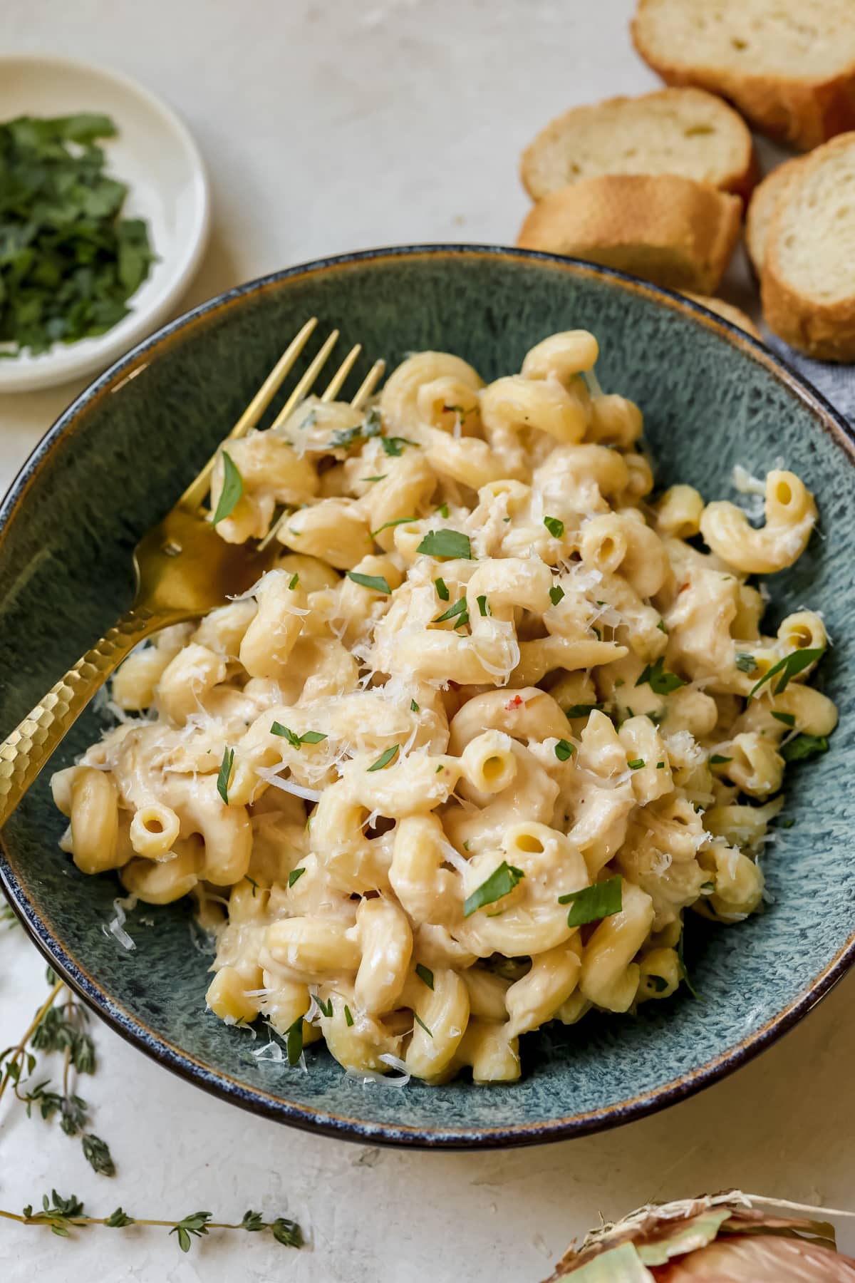 pasta in a blue bowl garnished with cheese and parsley. 