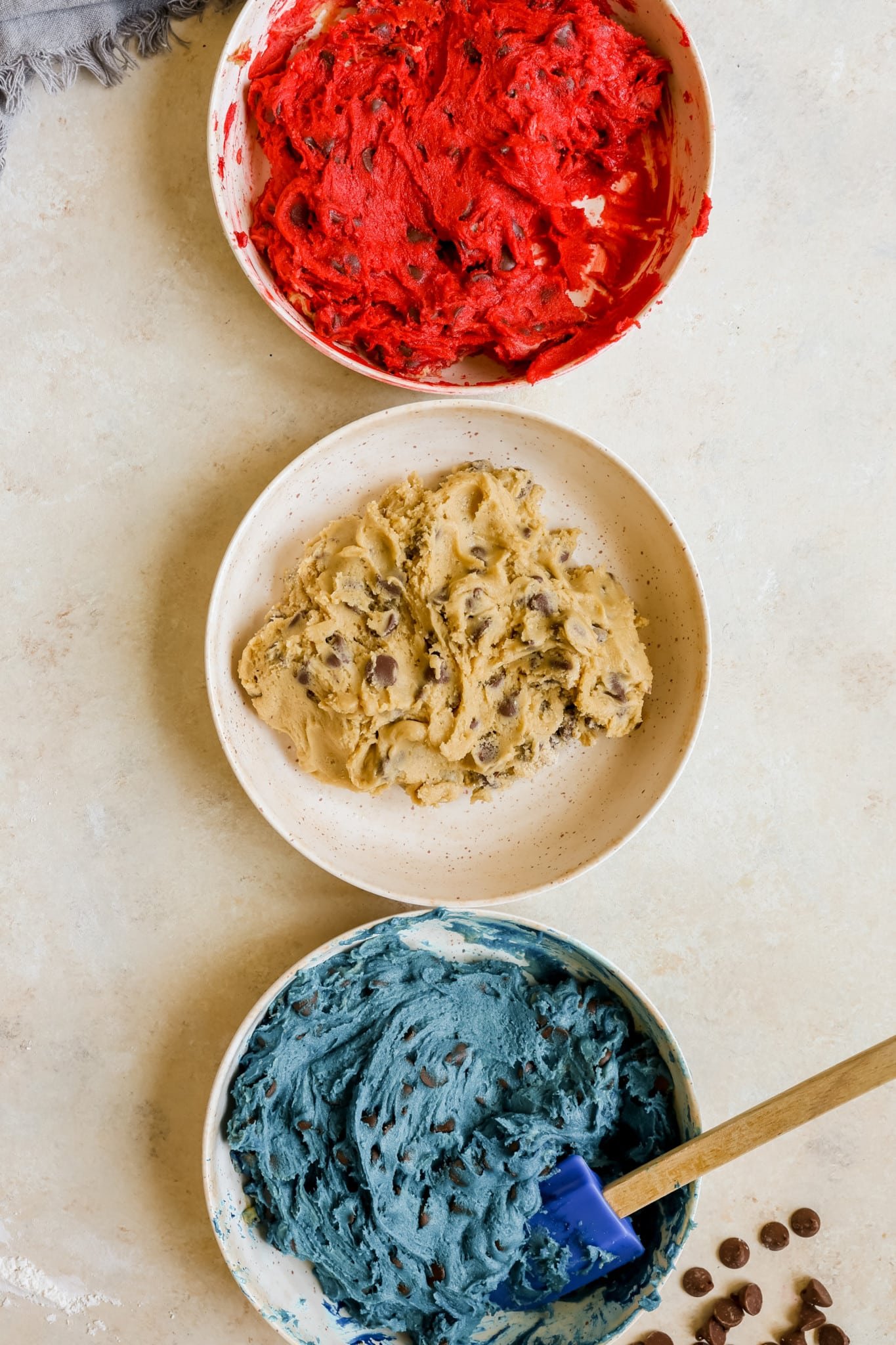 cookie dough in 3 bowls and colored with red and blue food coloring.