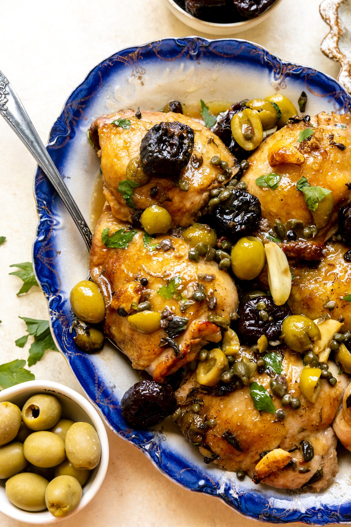 chicken thighs with green and black olives and spices on a blue plate