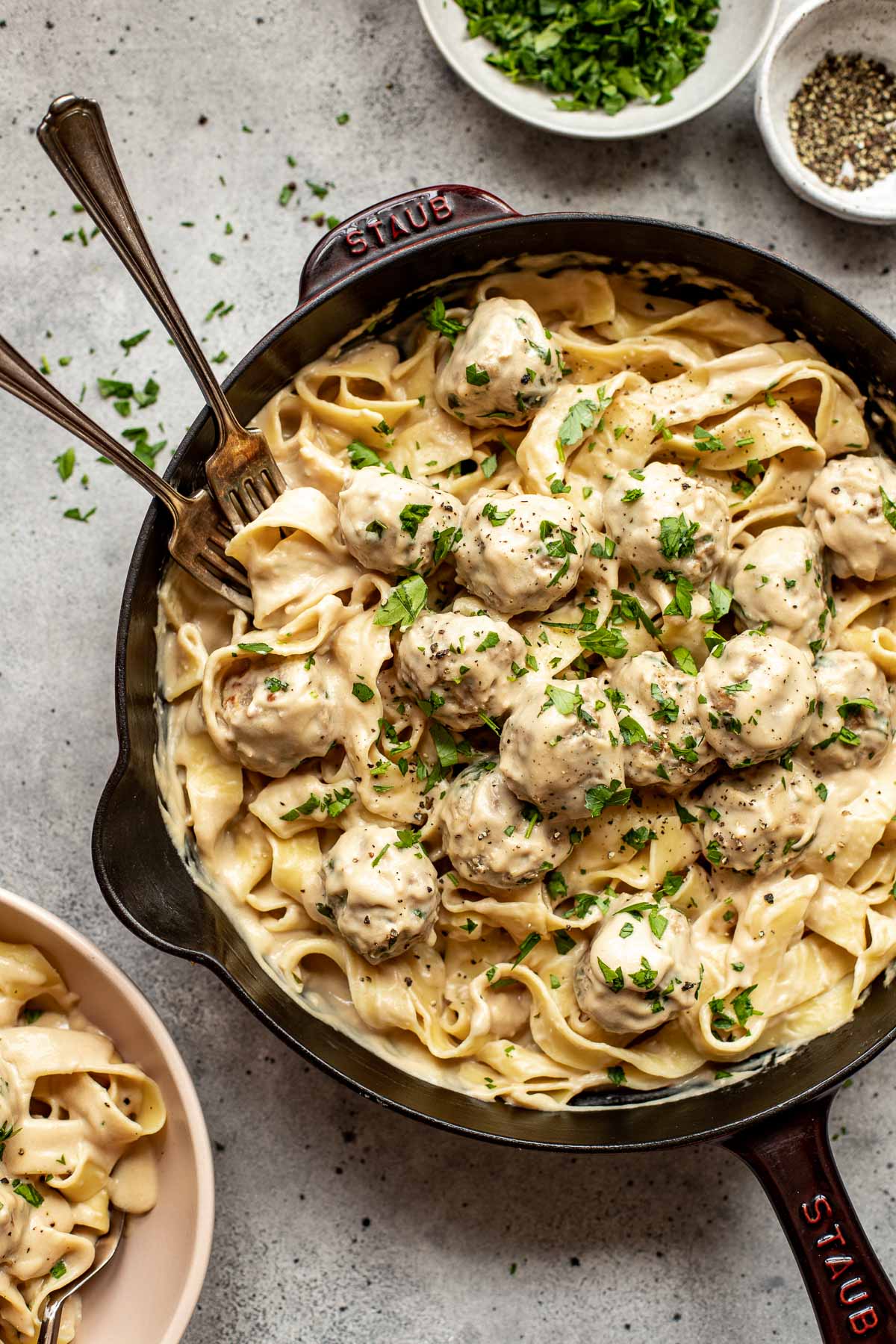 swedish meatballs with pasta garnished with parsley in a skillet. 