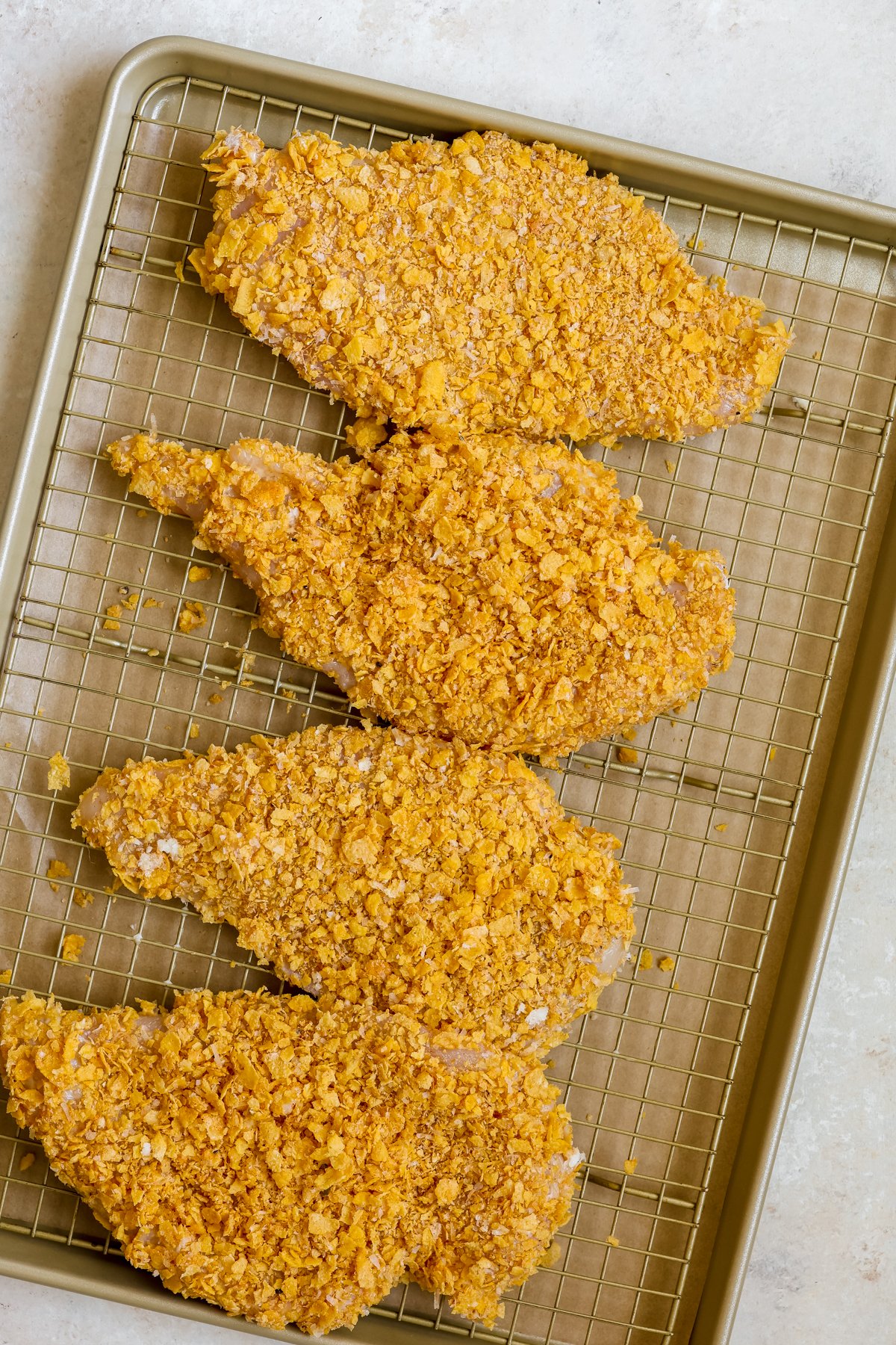 chicken coated in cornflakes on a baking sheet. 