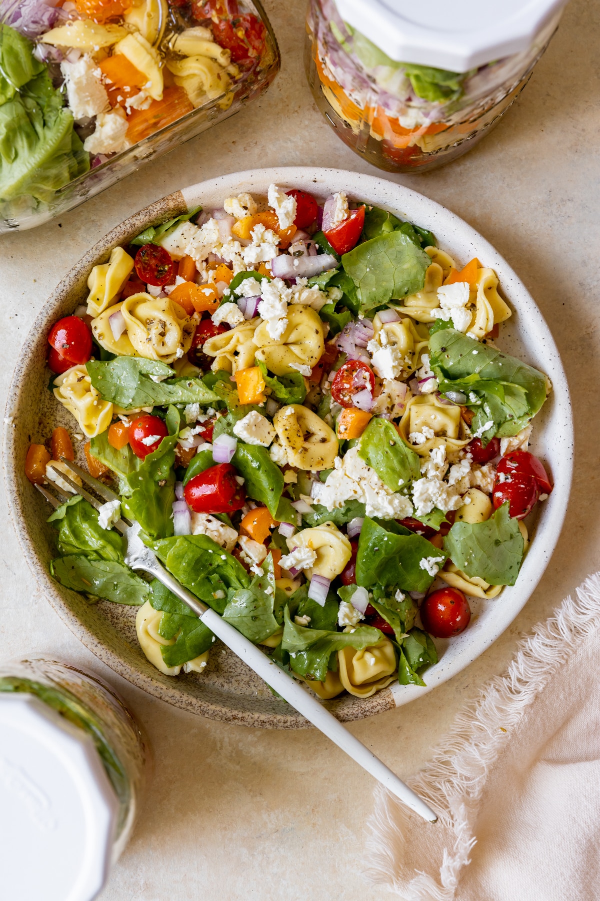 salad on a plate with cheese tortellini and colorful veggies.