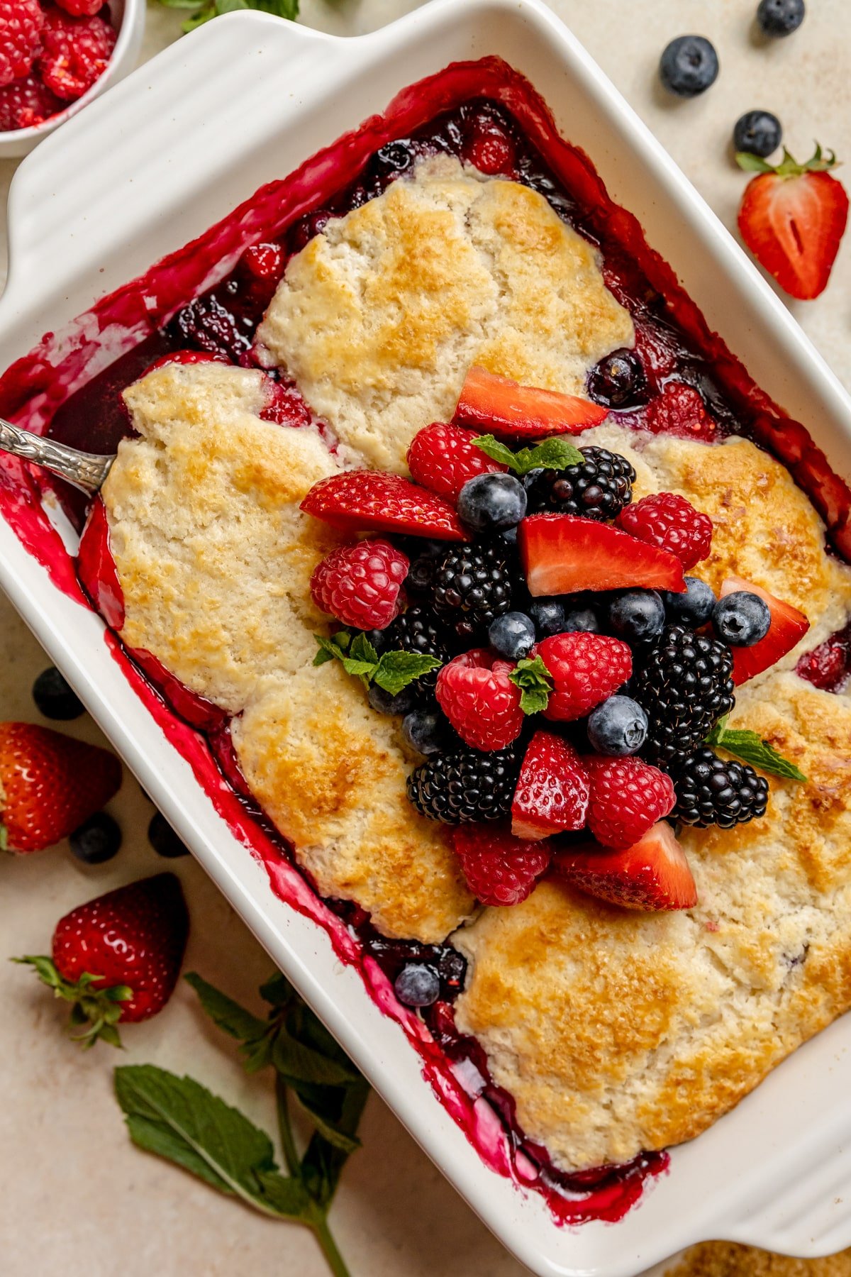 a freshly baked cobbler topped with berries and fresh mint. 