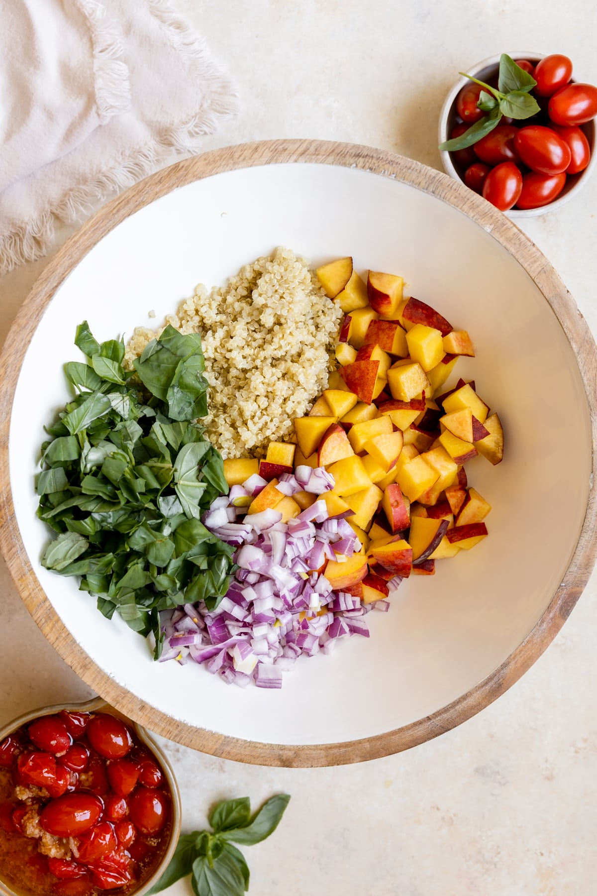 peaches, basil, quinoa and red onion in a large white salad bowl 