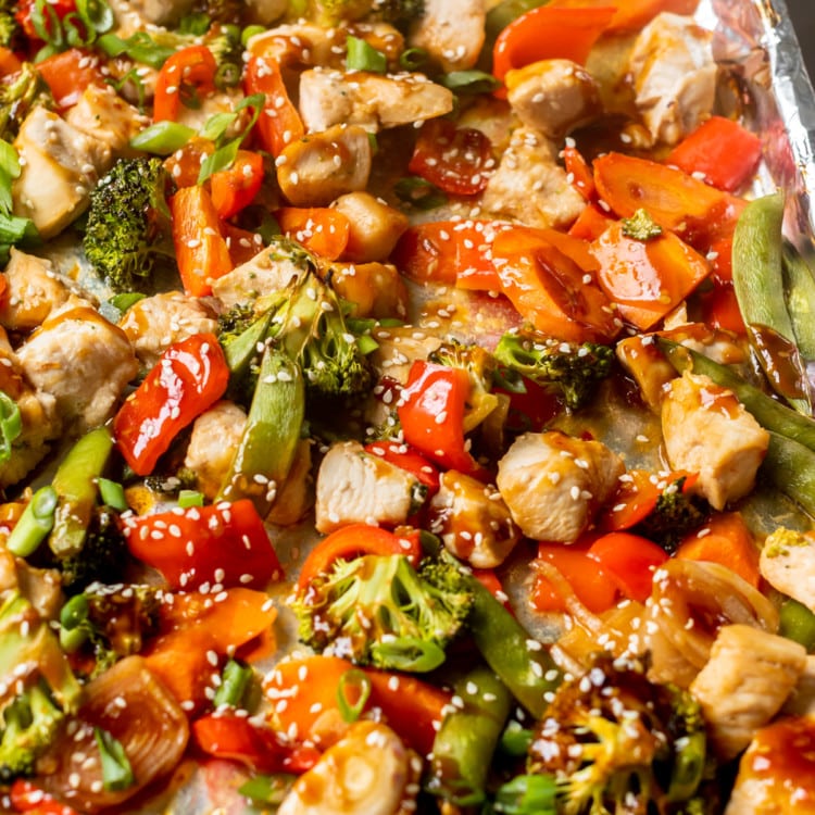 tray with chicken and veggies drizzled in sauce and sprinkled with sesame seeds