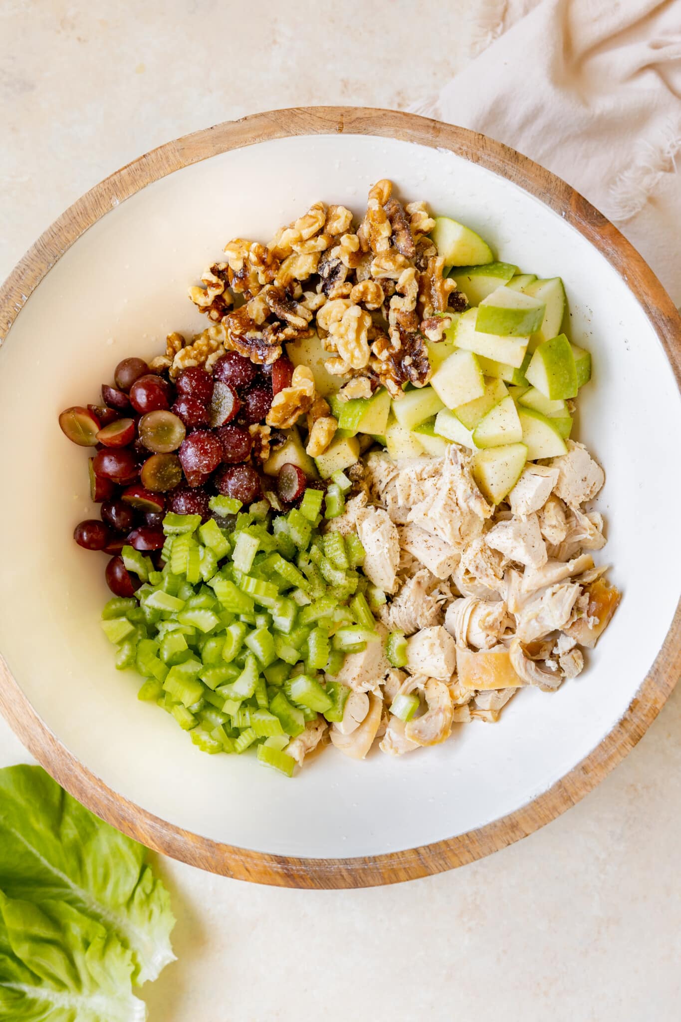 chicken, apple, walnuts, grapes and celery in a large white bowl.