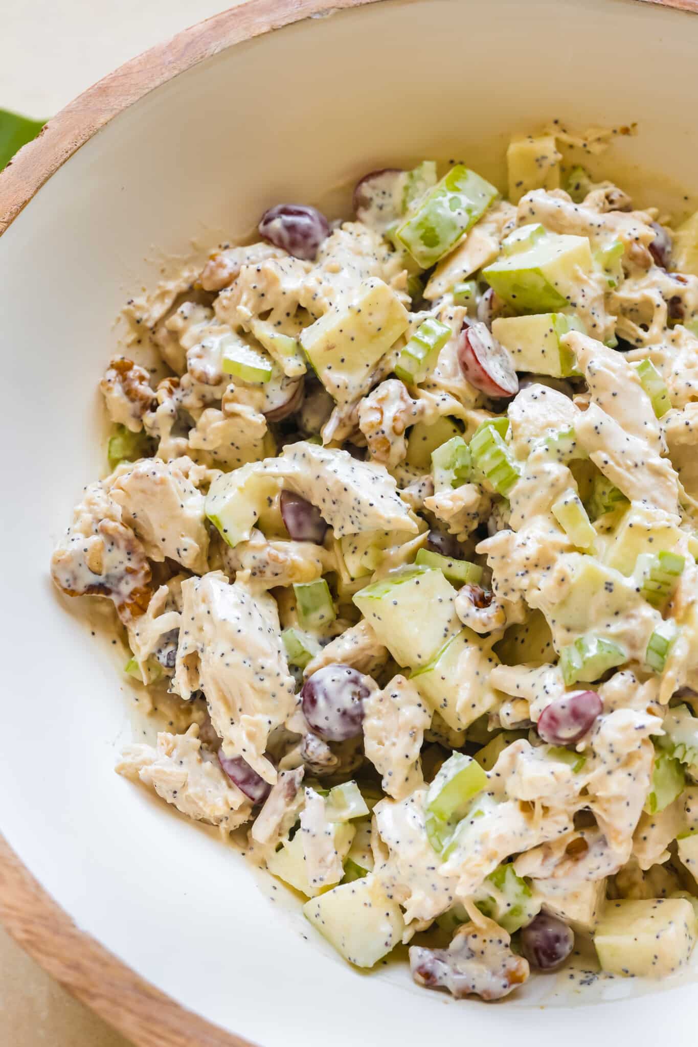 chicken, apples, grapes, walnuts tossed in a poppyseed dressing in a large white bowl.