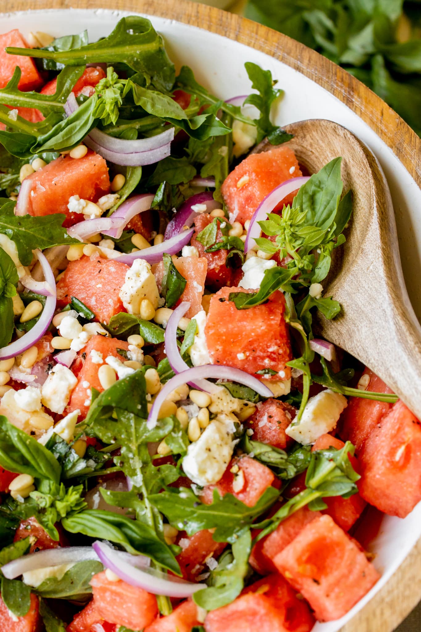 an up close image of a salad filled with feta, pine nuts, basil, and watermelon. 