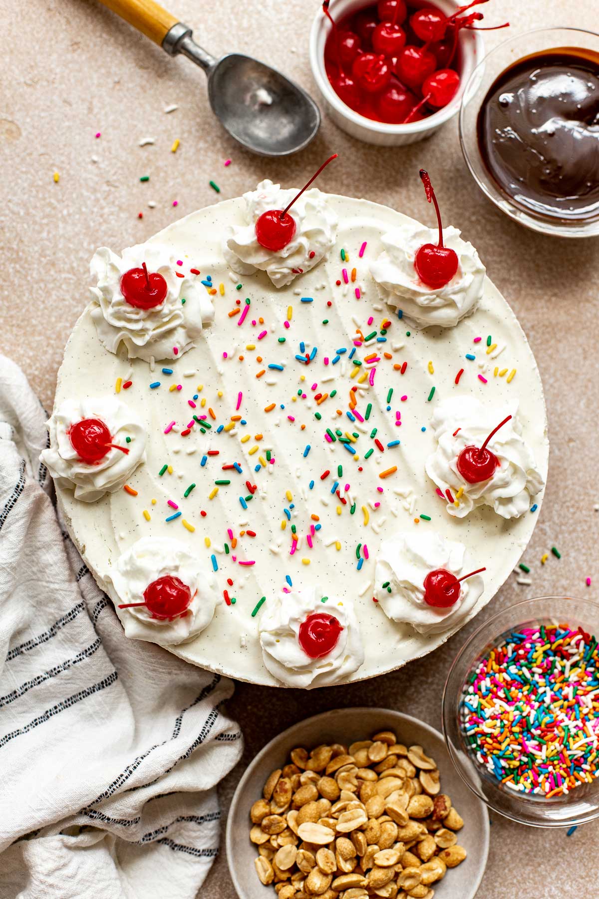 a photos of an ice cream cake decorated with cherries and rainbow sprinkles.