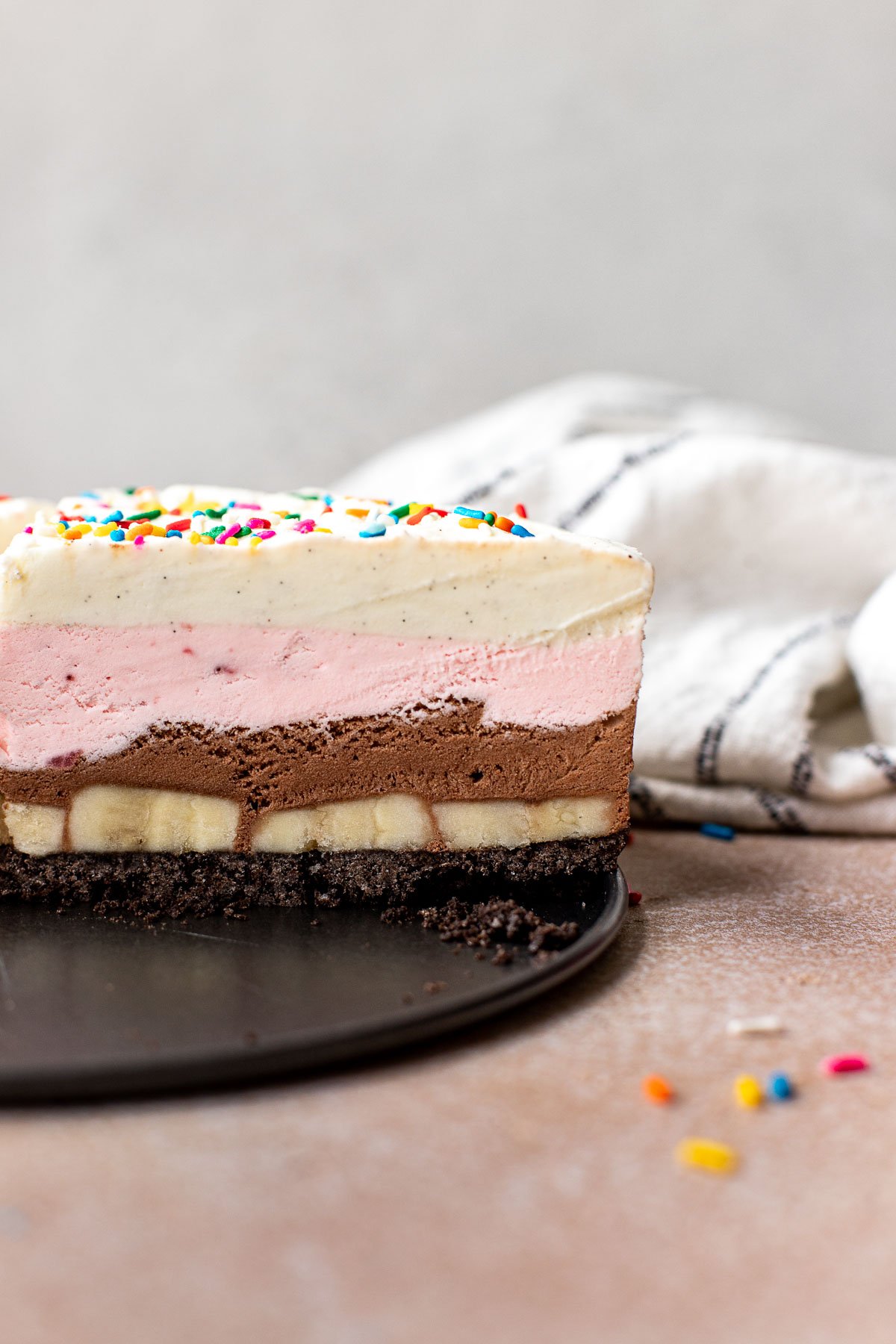 ice cream pie layered with strawberry, chocolate and vanilla ice cream and sprinkles on top. 