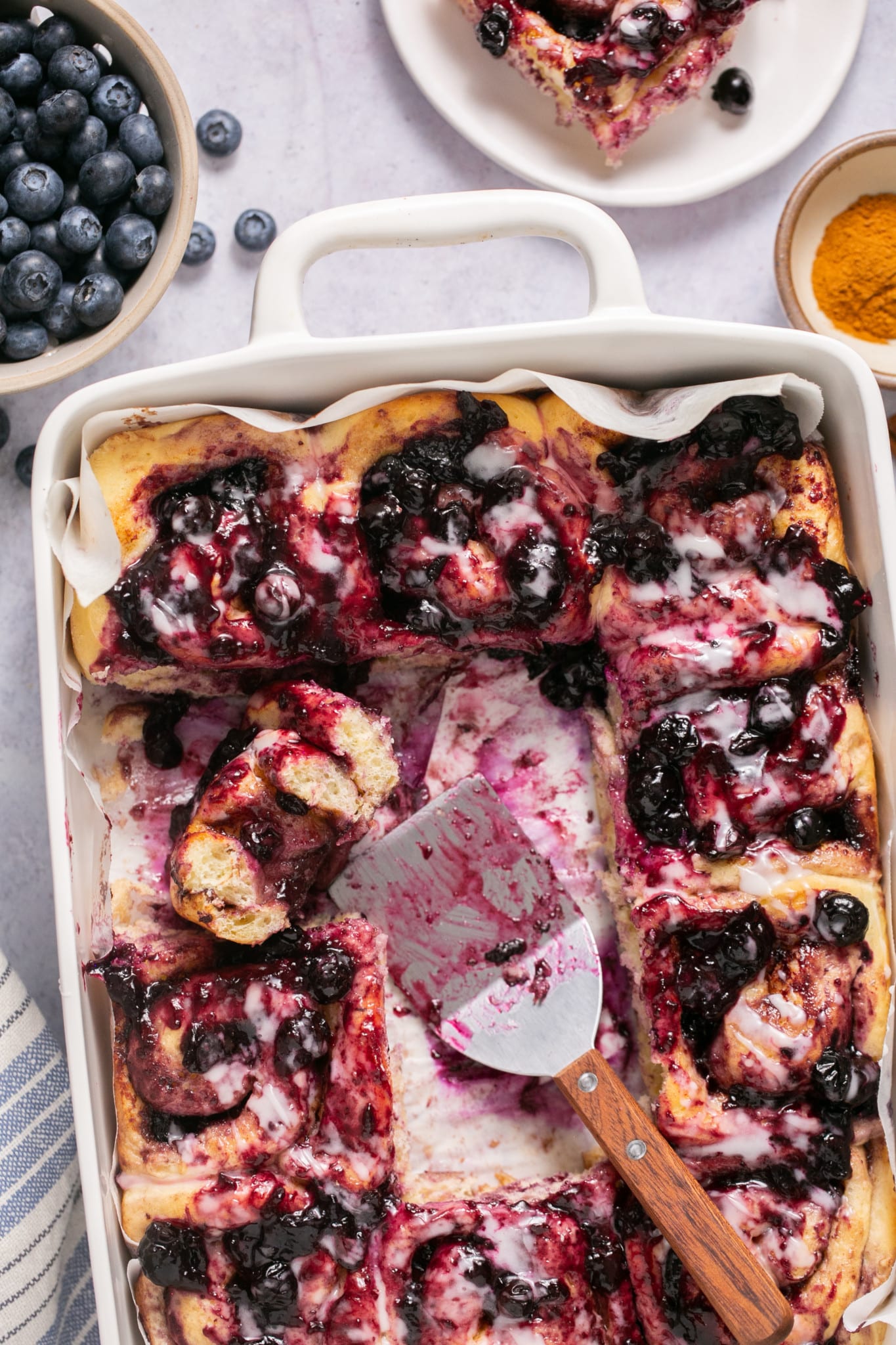 Freshly baked blueberry cinnamon rolls in a baking dish. 