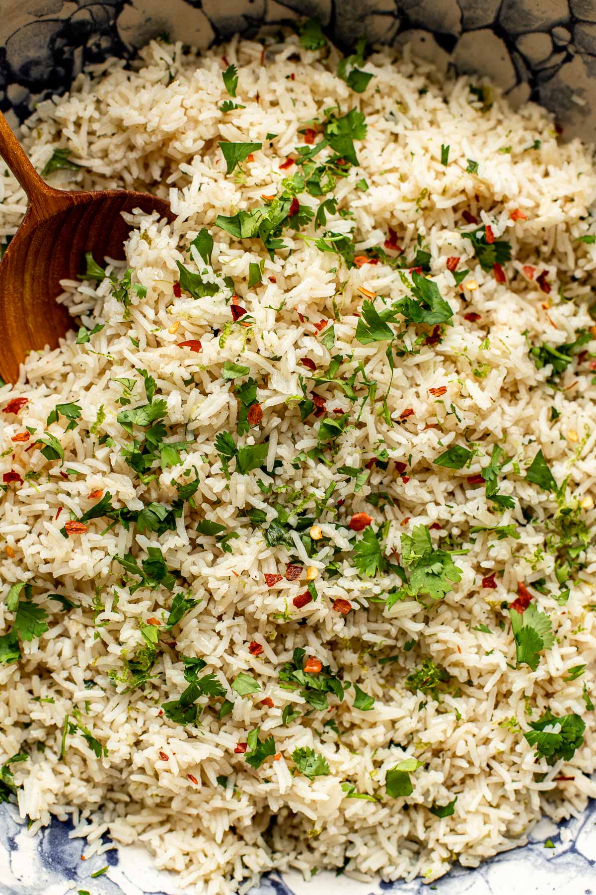 A close up image of rice with cilantro and chili flakes on top. 