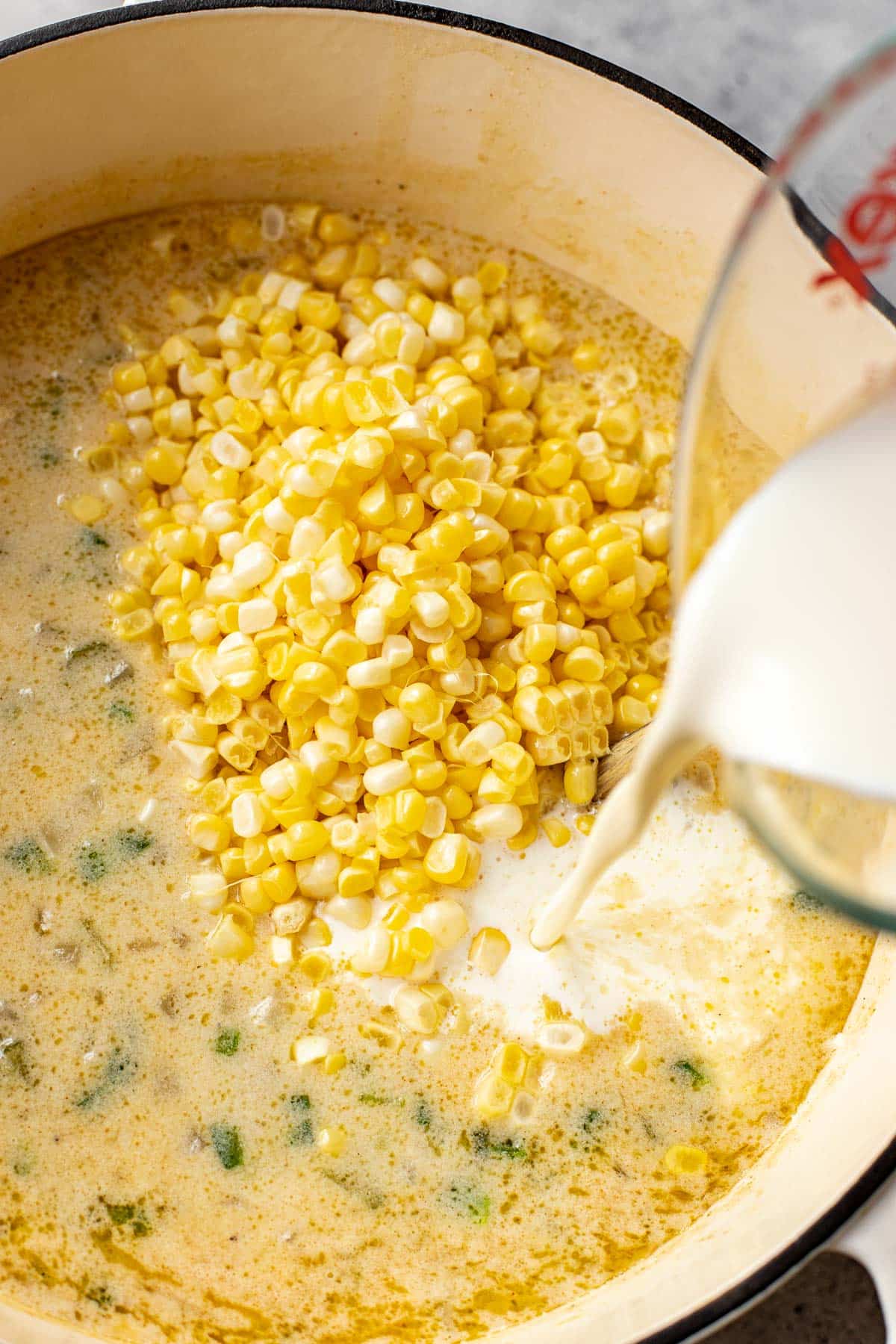 milk being poured into a corn chowder soup. 