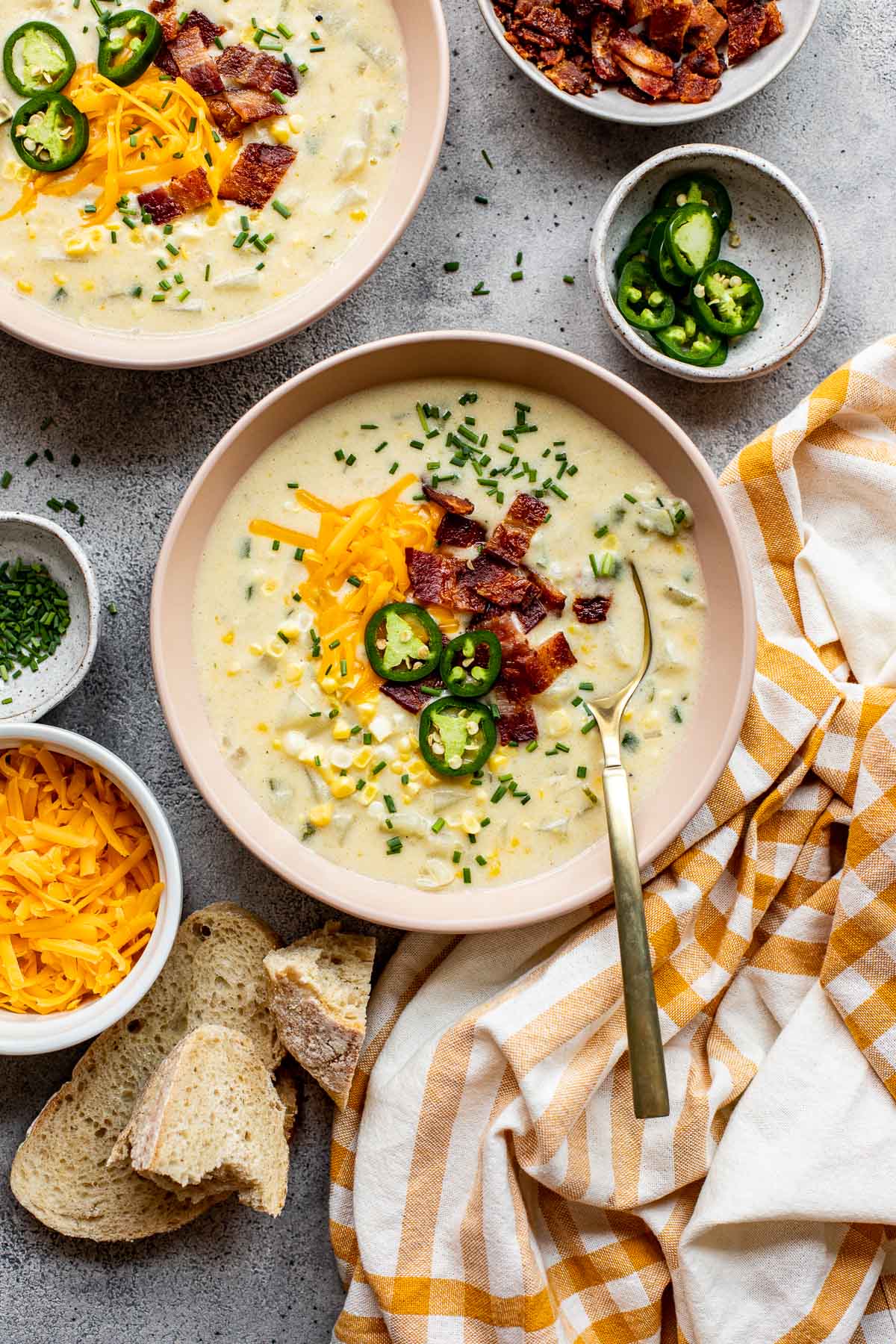 corn chowder in a pink bowl garnished with bacon, cheddar and jalapeno