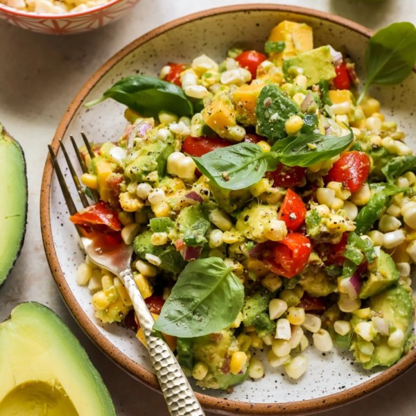speckled plate with a corn, avocado, tomato, basil salad