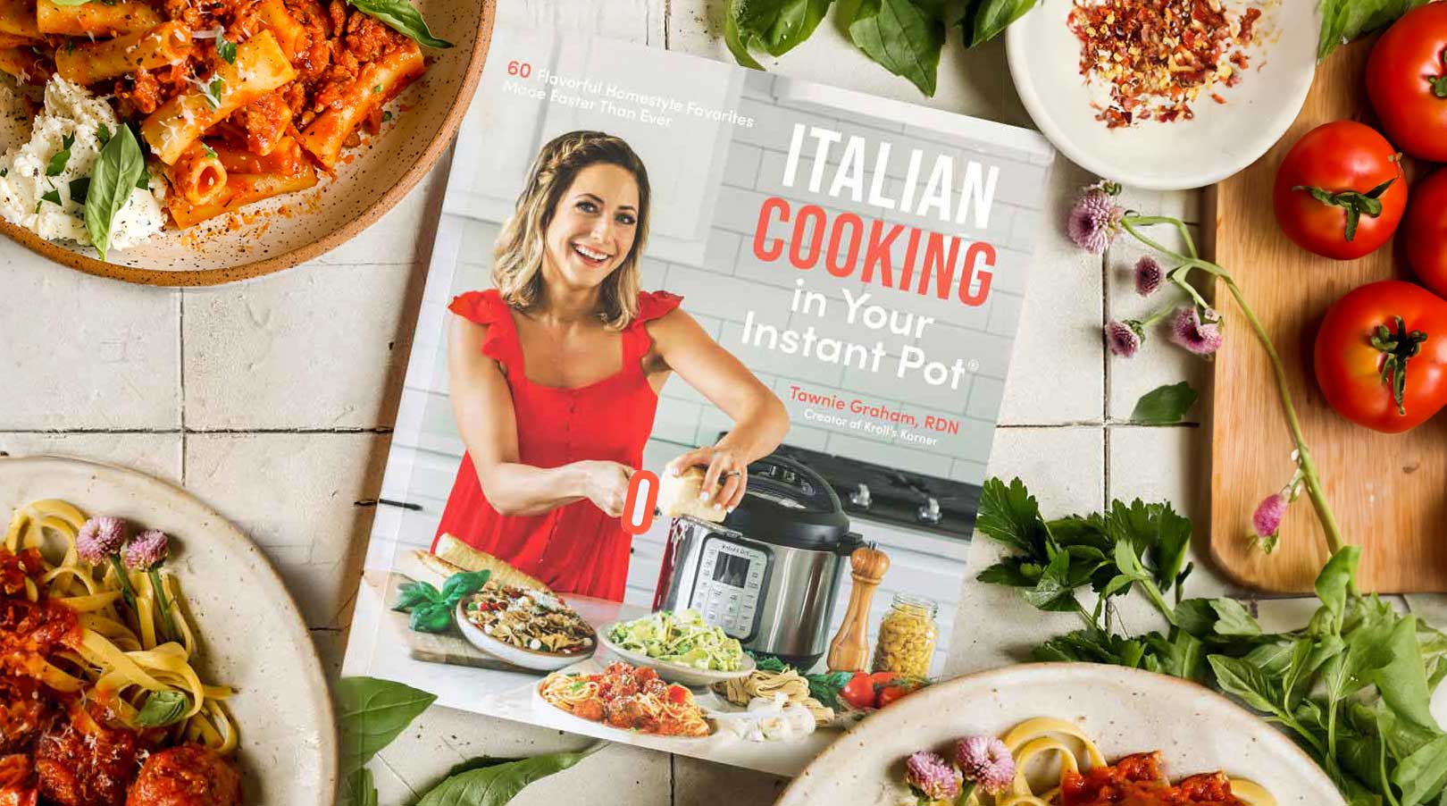 Overhead view of Tawnie's Italian cooking cookbook surrounded by fresh ingredients.