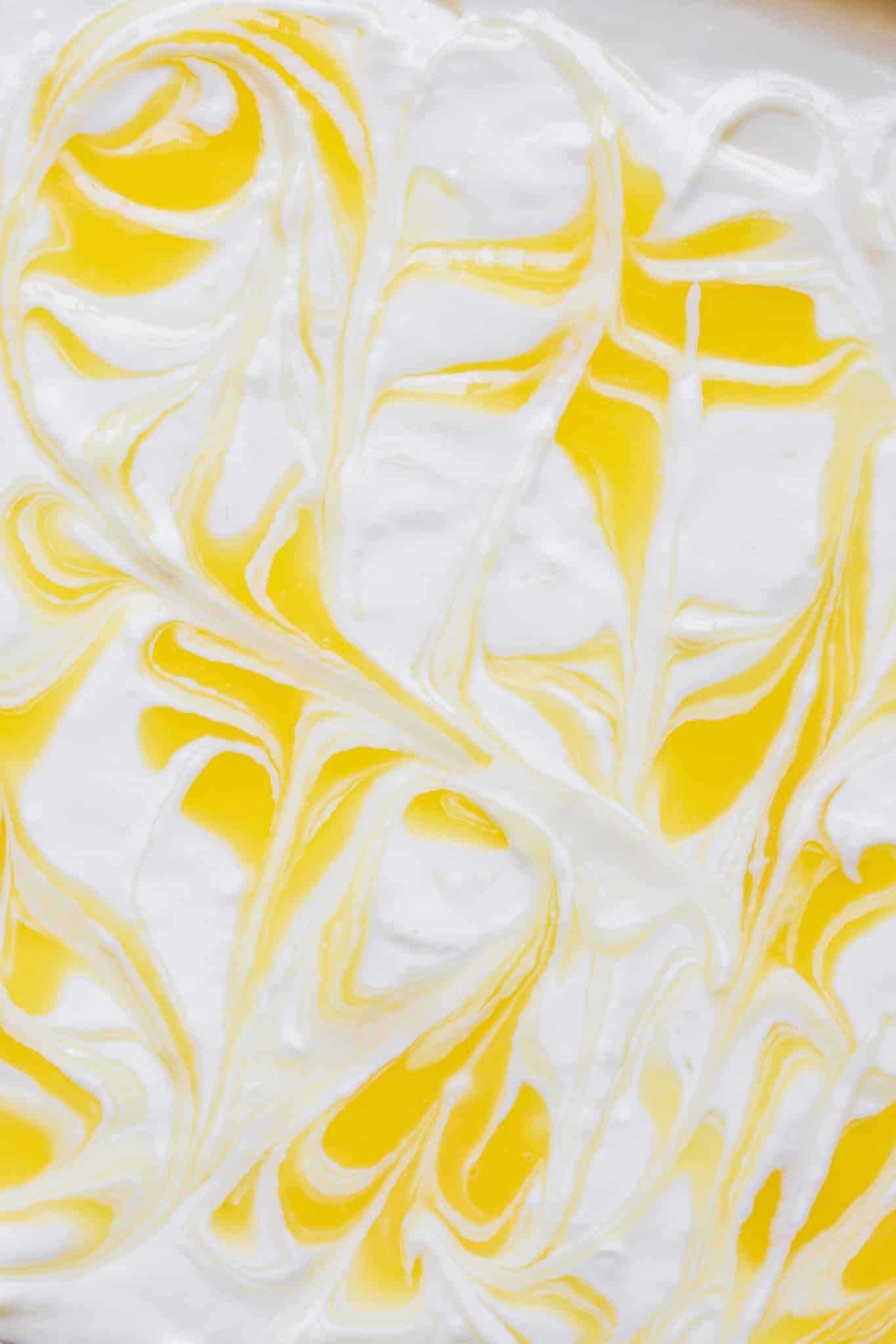 an up close image of lemon curd swirled into the cheesecake filling. 
