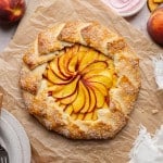 Peach galette chilling on piece of parchment paper after baking before serving.