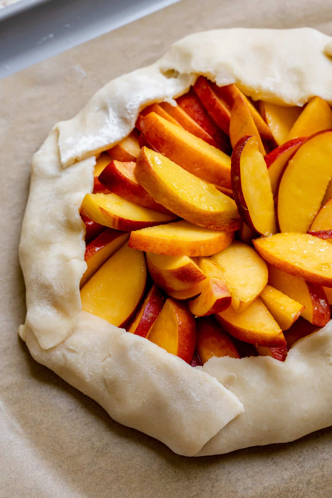 fresh peaches tucked away inside a homemade pie dough on a baking sheet. 