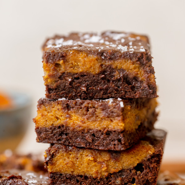 three pumpkin brownies stacked topped with powder sugar