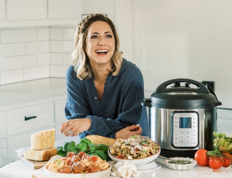 blogger tawnie graham in a kitchen with an instant pot and several dishes of food
