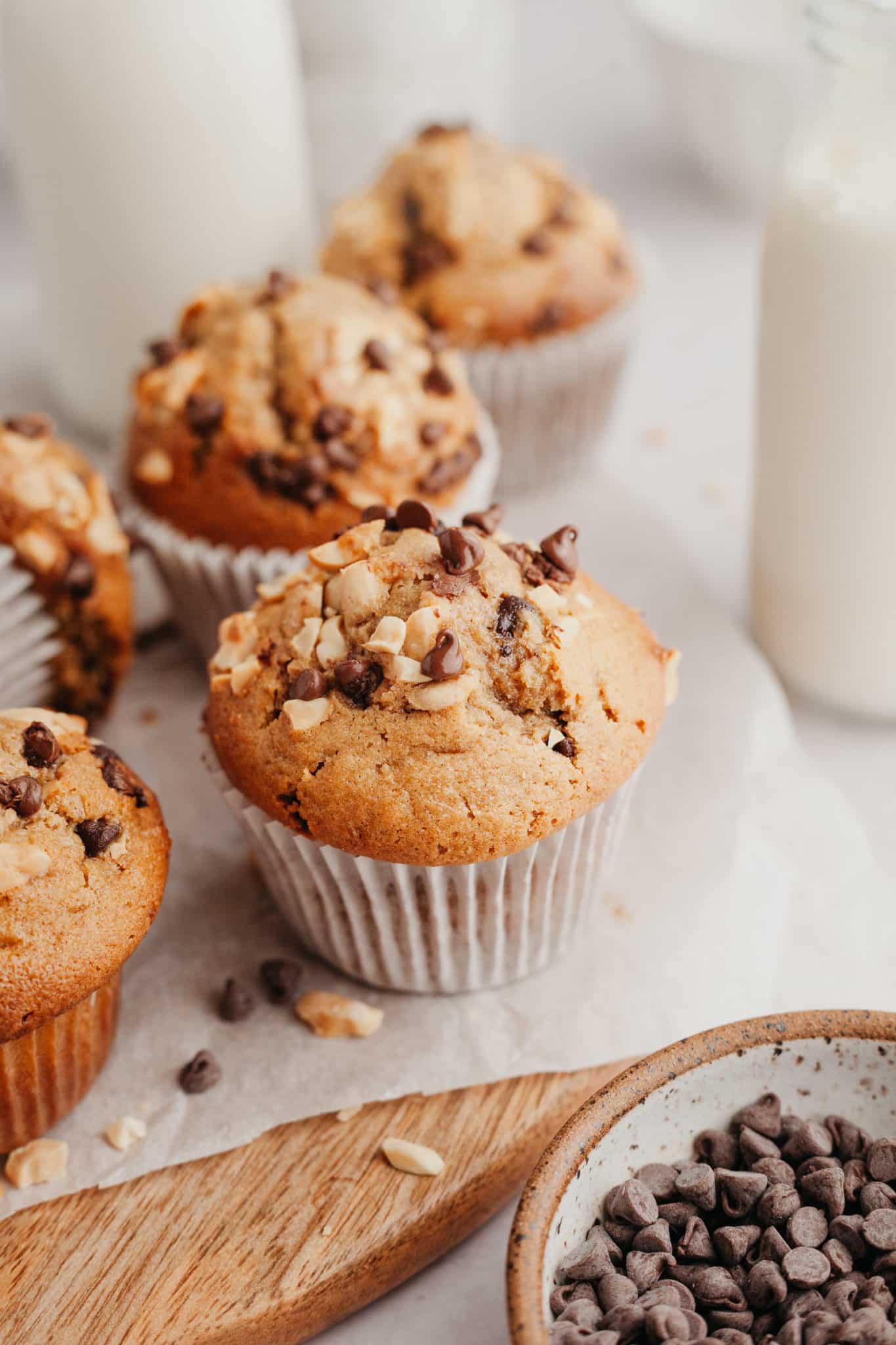 muffins on parchment paper garnished with peanuts and chocolate chips. 