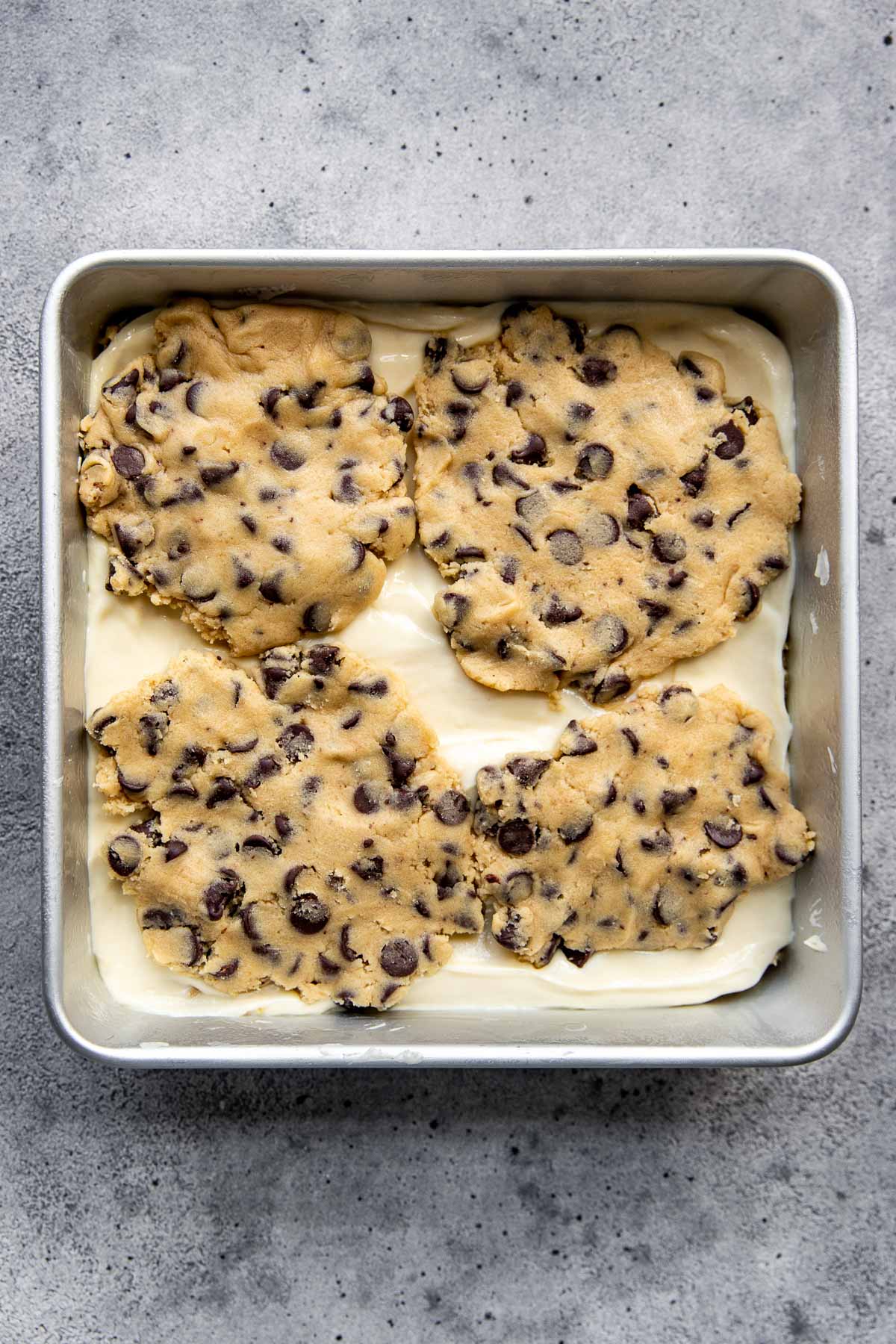 Cookie dough on top of a cheesecake filling in a 8x8 pan.