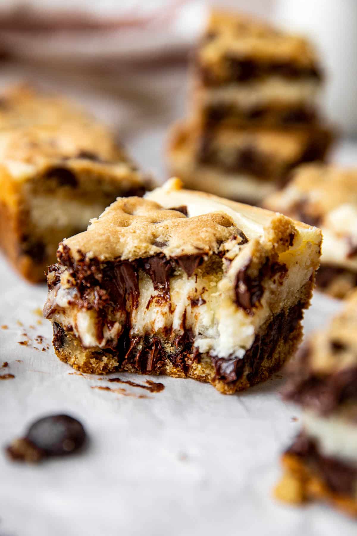 A close up image of a cheesecake cookie bar with a bite taken from it. 