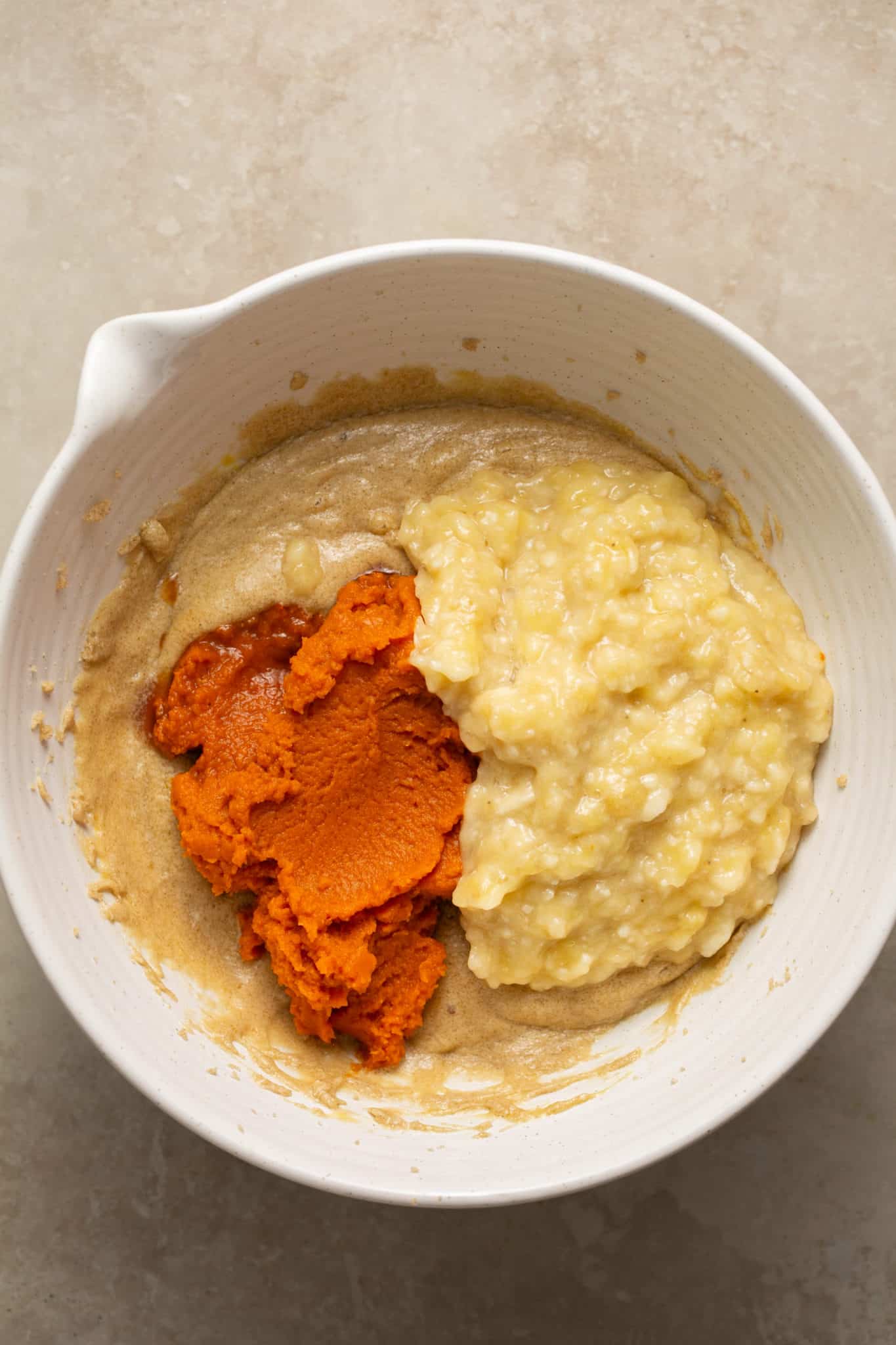 pumpkin puree and mashed bananas in a white mixing bowl.