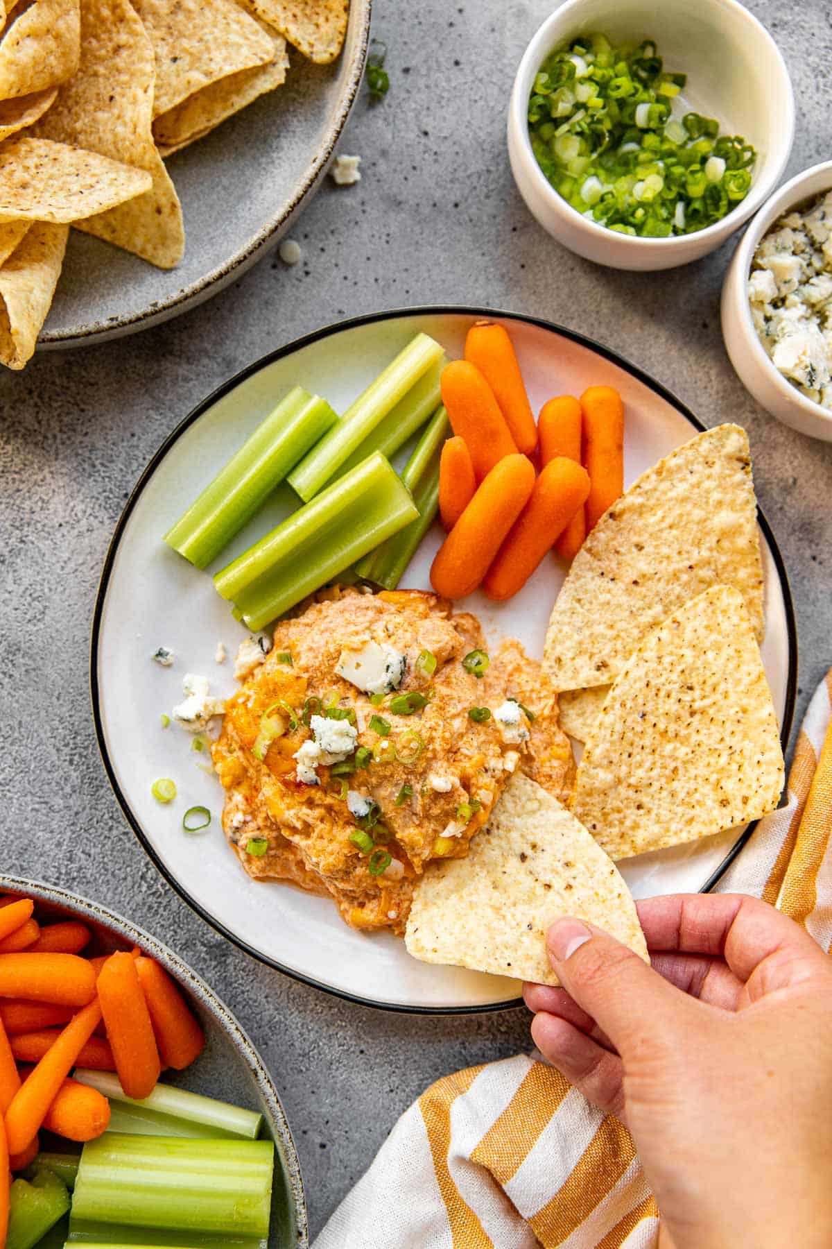 buffalo chicken dip on a plate with chips, celery and baby carrots. 