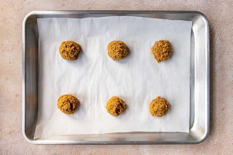 six balls of cookie dough on a baking sheet