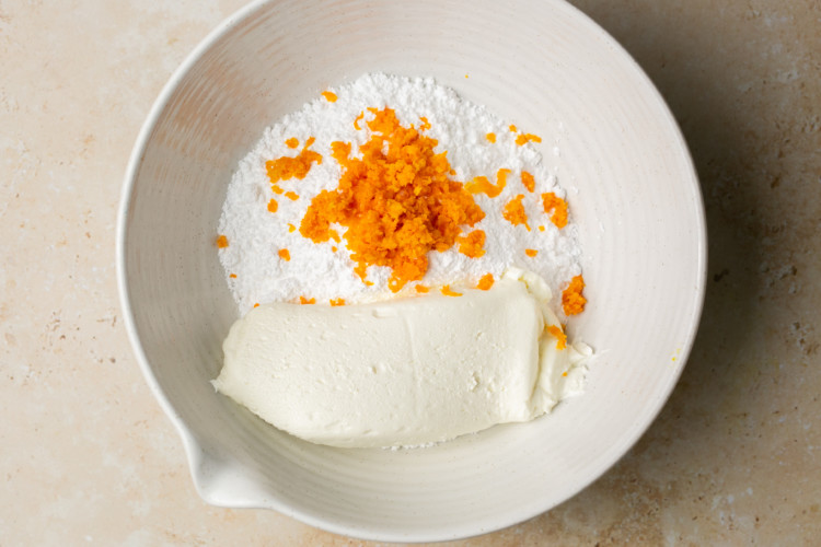 powdered sugar, cream cheese, and orange zest in a bowl