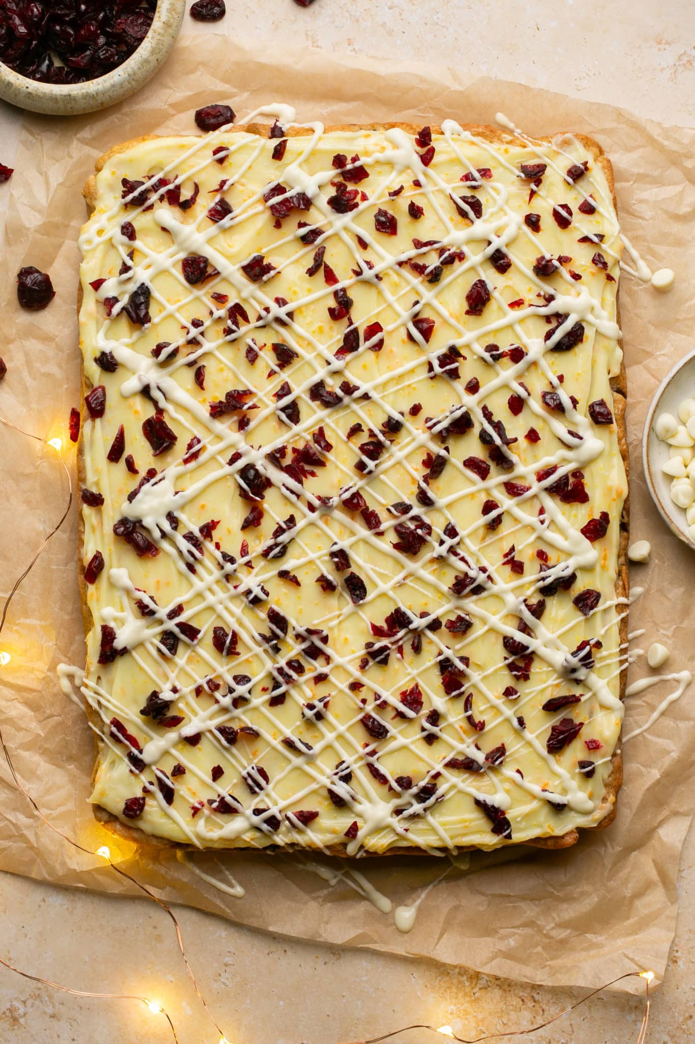 white chocolate and cranberries on top of bliss bars on parchment paper. 