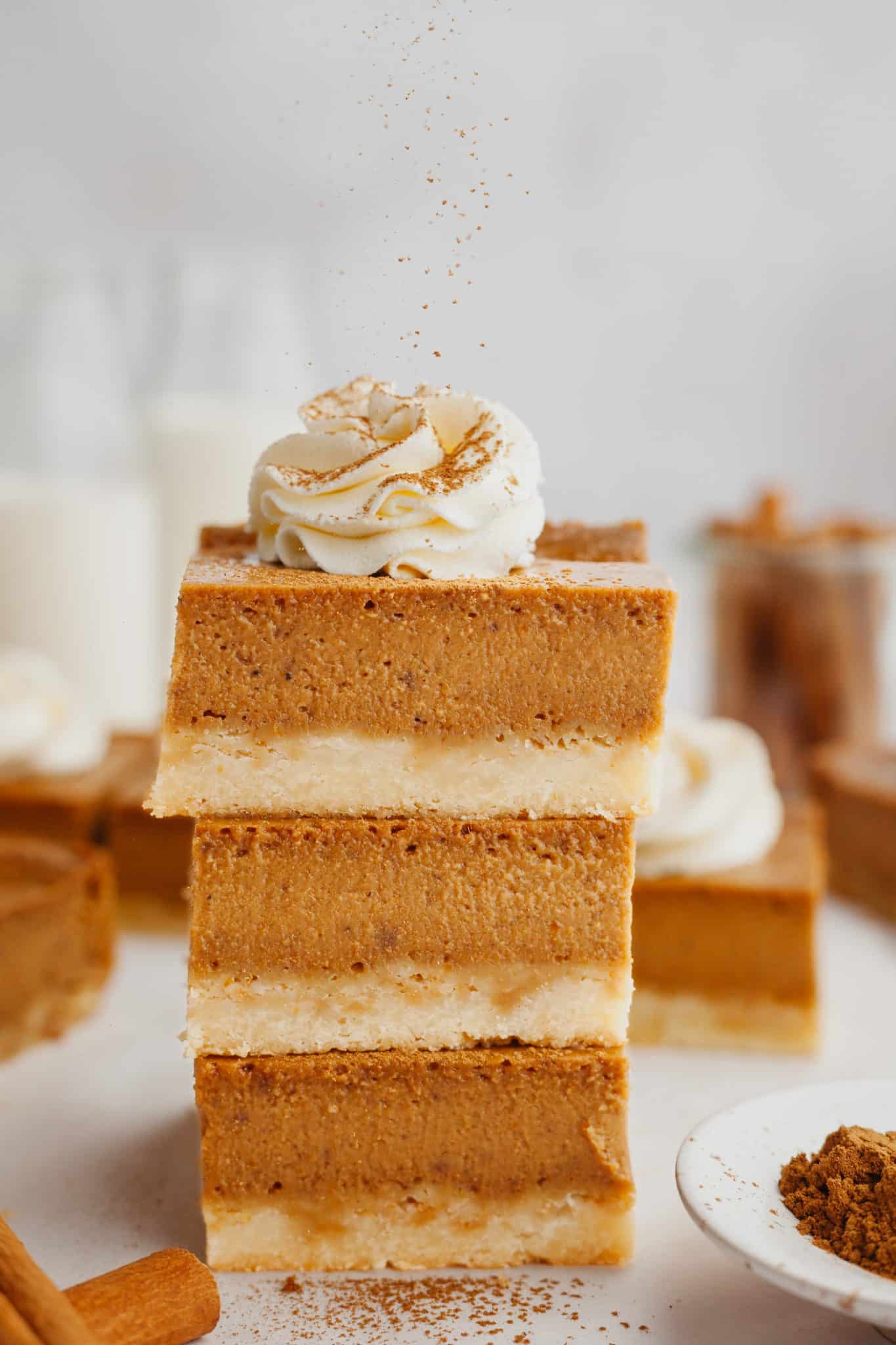 a stack of pumpkin pie bars with cinnamon sprinkled on top. 