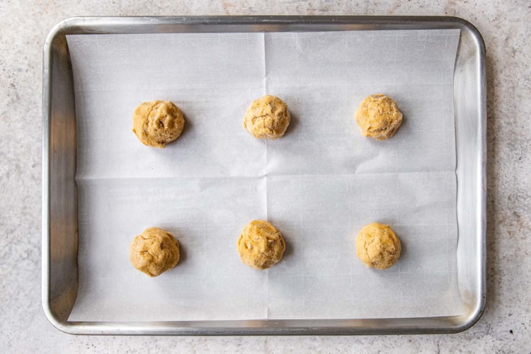 six balls of peanut butter cookie dough on a baking sheet