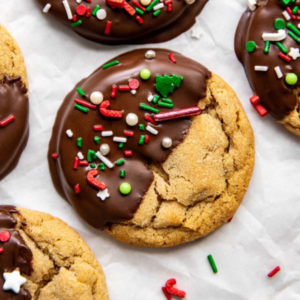 close up of peanut butter cookie half covered with chocolate and white green and red sprinkles