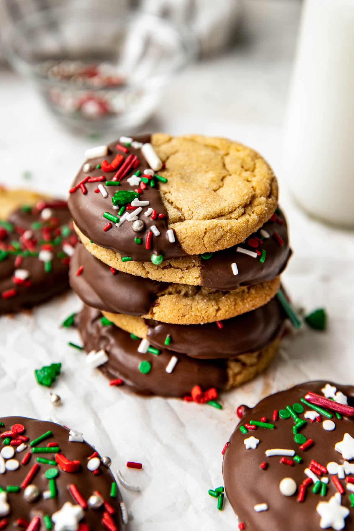 a stack of peanut butter cookies that are dipped in dark chocolate and decorated with christmas sprinkles. 